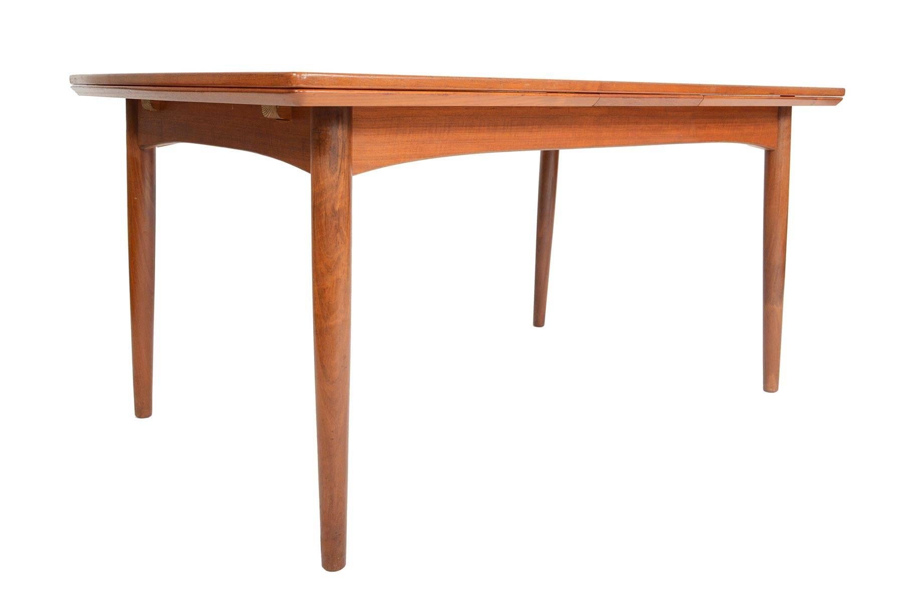 This beautiful teak dining table was designed and constructed in Denmark in the mid-1960s. Featuring handsomely tapered legs and bowed edges, this table is executed with wonderful detailing throughout. Two Dutch leaves pull out to almost double the