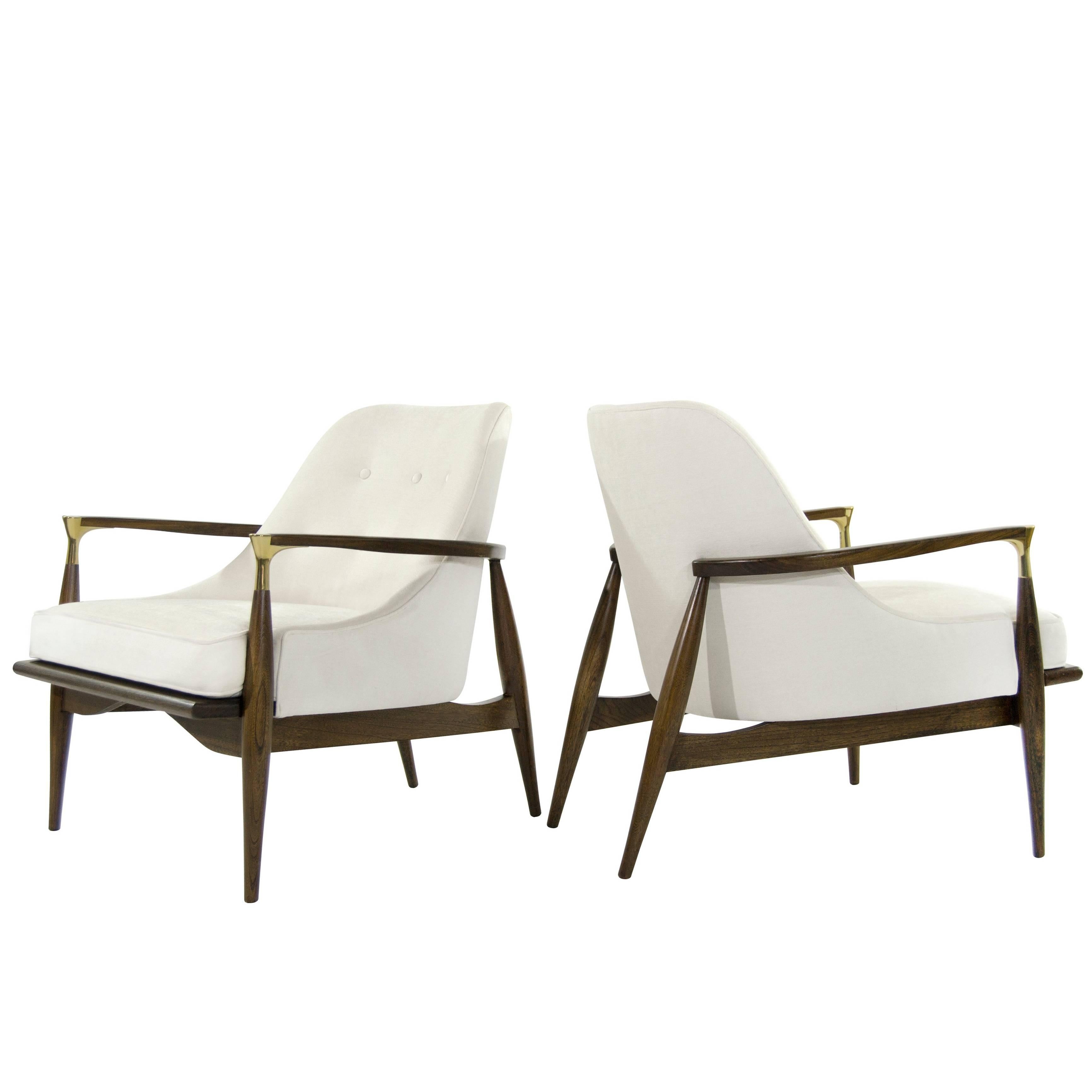 Rare lounge chairs in the style of Ib Kofod-Larsen. Featuring brass details on arms. Newly upholstered in soft off-white wool. Sculptural walnut frames completely restored. Set of 4 available. Priced individually.