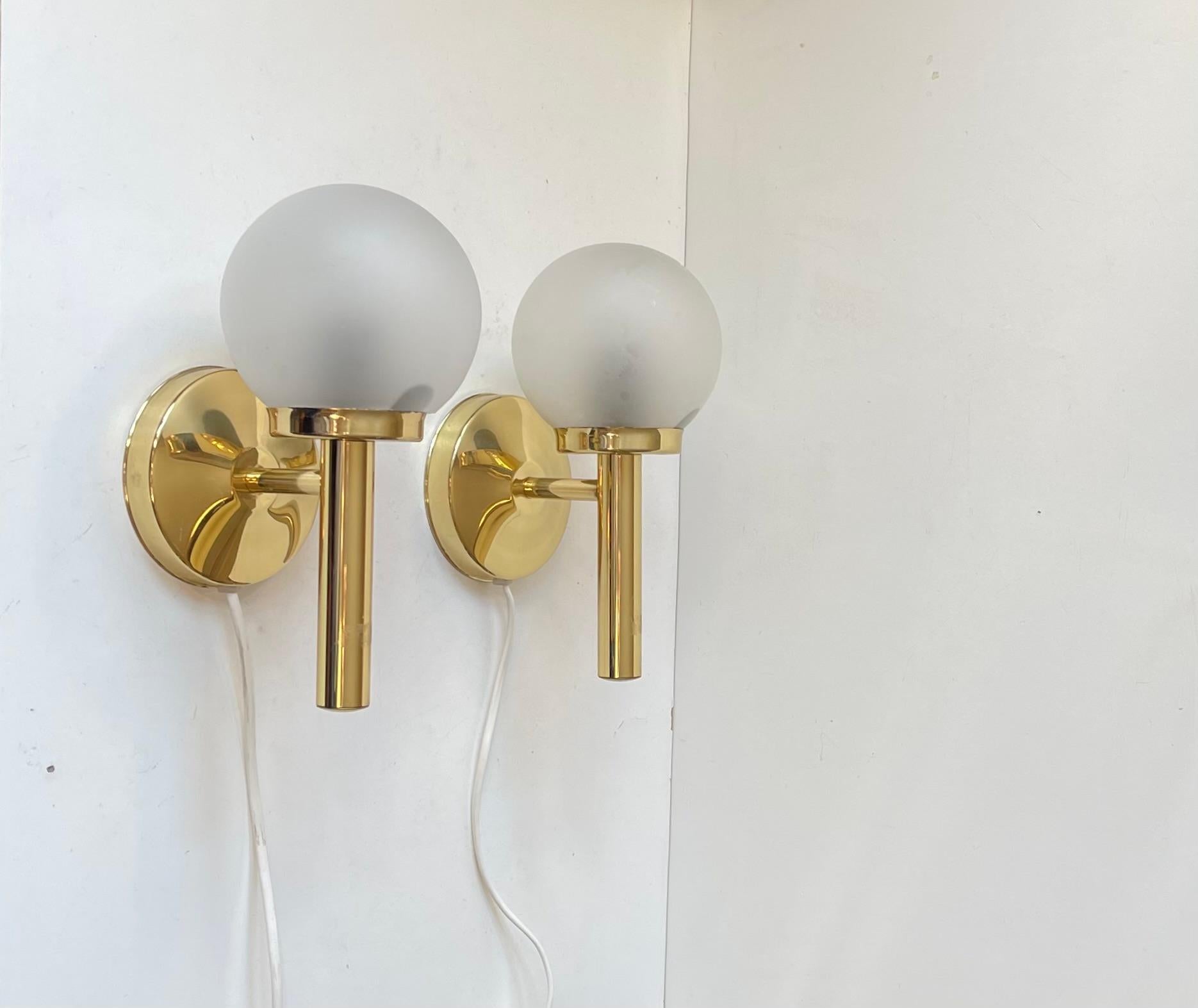 Apliques de pared de latón de renacimiento Art Déco con pantallas esféricas de cristal esmerilado/mate fabricados y diseñados por Abo Metalkunst en un estilo que recuerda al de Hans-Agne Jakobsson y Michael Anastassiades unos 40 años después.
