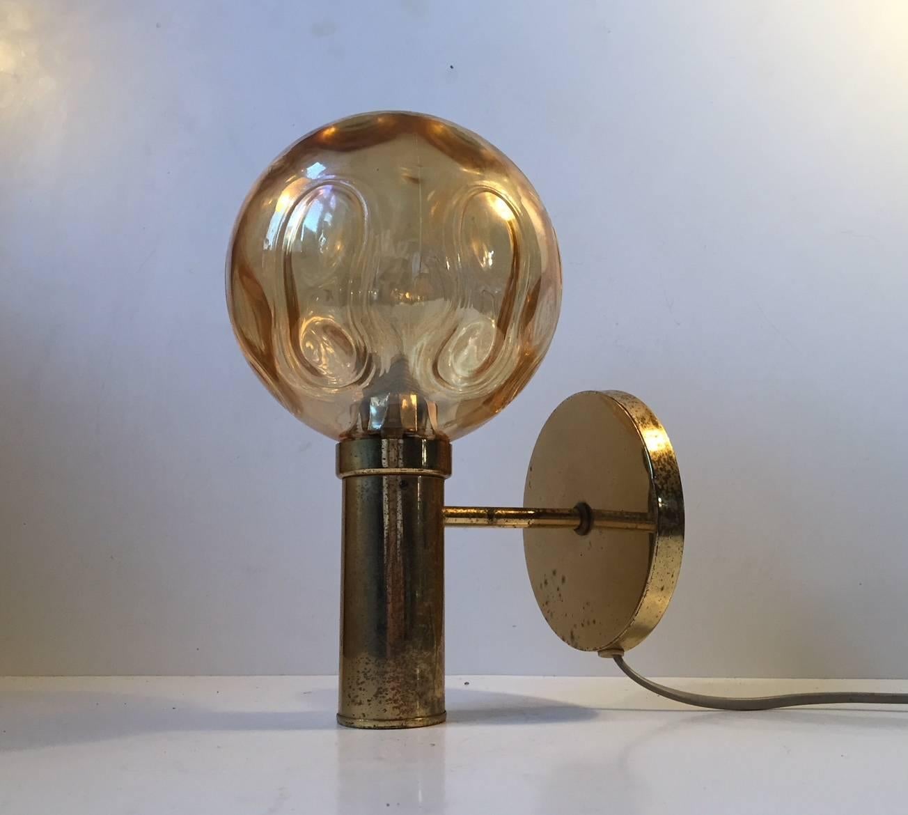 Lounge sconce with spherical amber colored optical glass shade manufactured and designed by Vitrika in a style reminiscent of Hans-Agne Jakobsson. Nice vintage and working order with a rich patina to the brass frame. Fitted with E27 lightbulb up to
