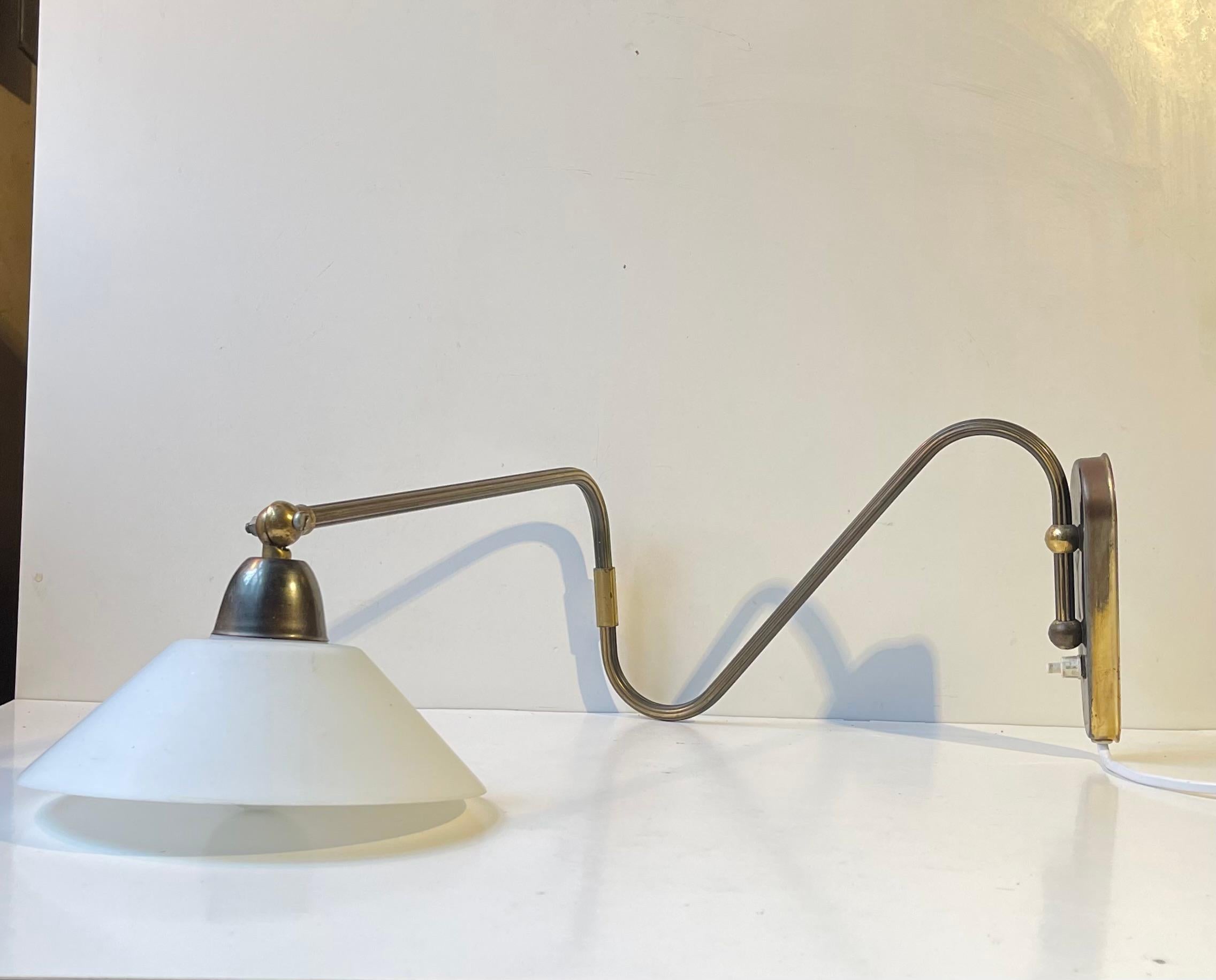 Fully adjustable articulated wall light/sconce composed of a brass 'body' (rod and base) installed with a matte opaline glass shade. It was designed and manufactured by Laoni in Copenhagen, Denmark. The style is reminiscent of Svend Aage