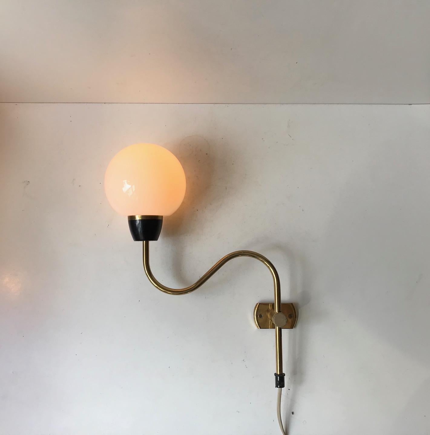 Fully adjustable wall lamp composed of a flower shaped brass body installed with a opaline ball shade. It was designed and manufactured during the 1960s in Denmark. The style is reminiscent of Svend Aage Holm-Sørensen, Paavo Tynell and Vilhelm