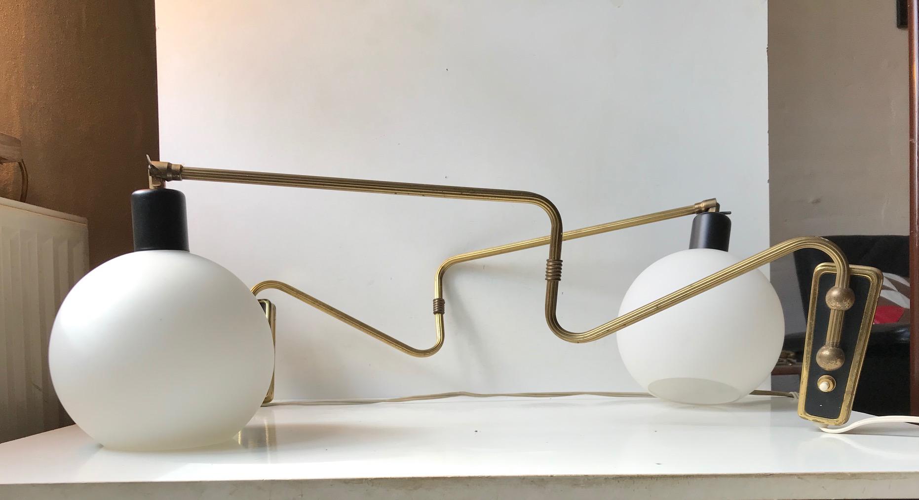 A pair of fully adjustable wall lamps composed of a brass 'body' installed with a opaline ball shade. Designed and manufactured by Laoni in Copenhagen, Denmark. The style is reminiscent of Svend Aage Holm-Sørensen. The shade may have been a later
