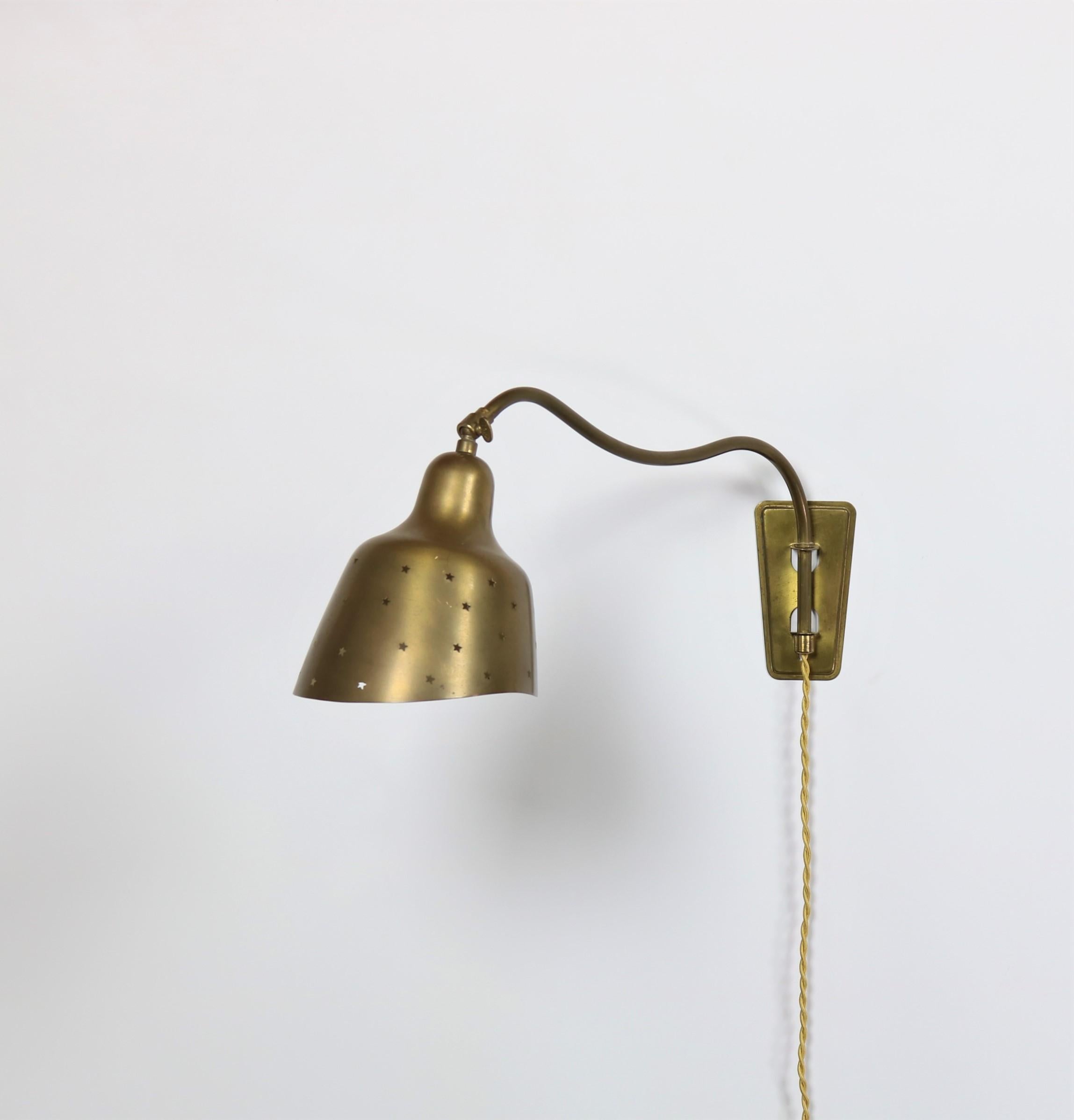Adjustable wall lamp in beautifully patinated solid brass produced in the early 1950s by Fog & Mørup and attributed to Vilhelm Lauritzen. The shade is perforated in star shapes which allows for an amazing effect when the lamp is lit. Great original