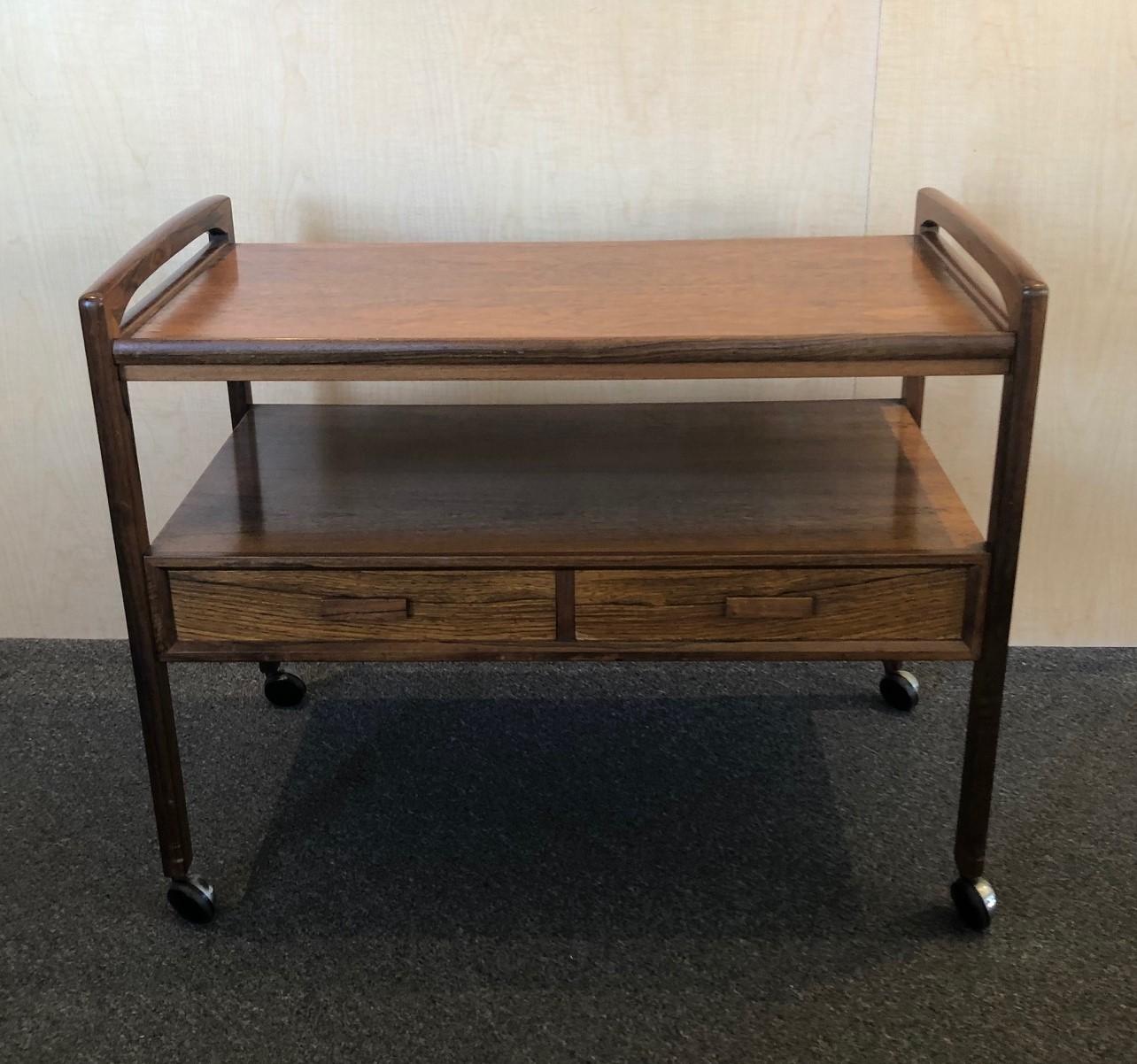 Rare Danish modern Brazilian rosewood bar / tea / TV cart by Arrebo Mobler of Denmark, circa 1960s. This trolley cart, which can be used as a side table, is typical of the Danish design during the 1960s with curved handles and rounded edges; it also