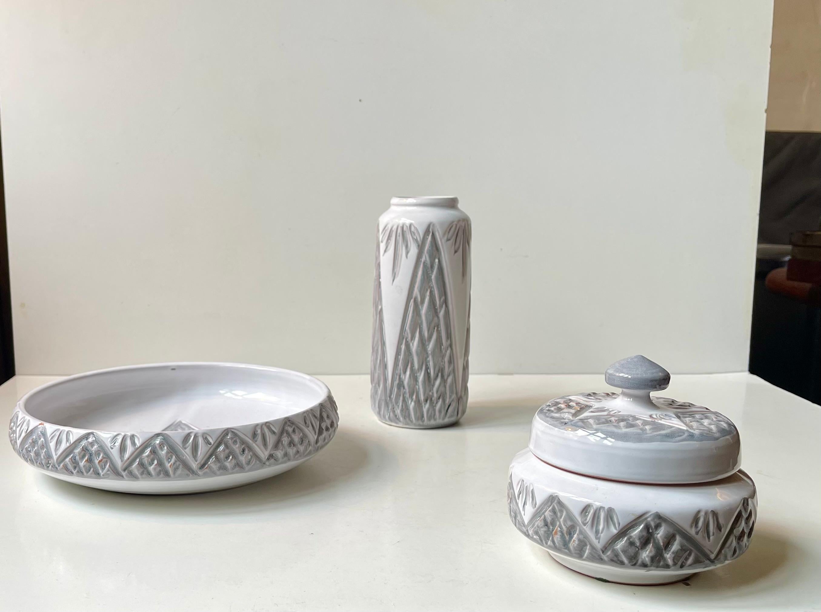 Vasetto, ciotola e vaso coordinati di Dissing Keramik in Danimarca. Realizzato negli anni '70. Motivi incisi in stile Sgrafitto evidenziati con smalto grigio su sfondo bianco. Misure: H: 18/11/5 cm, Diametro: 22/12/9 cm.