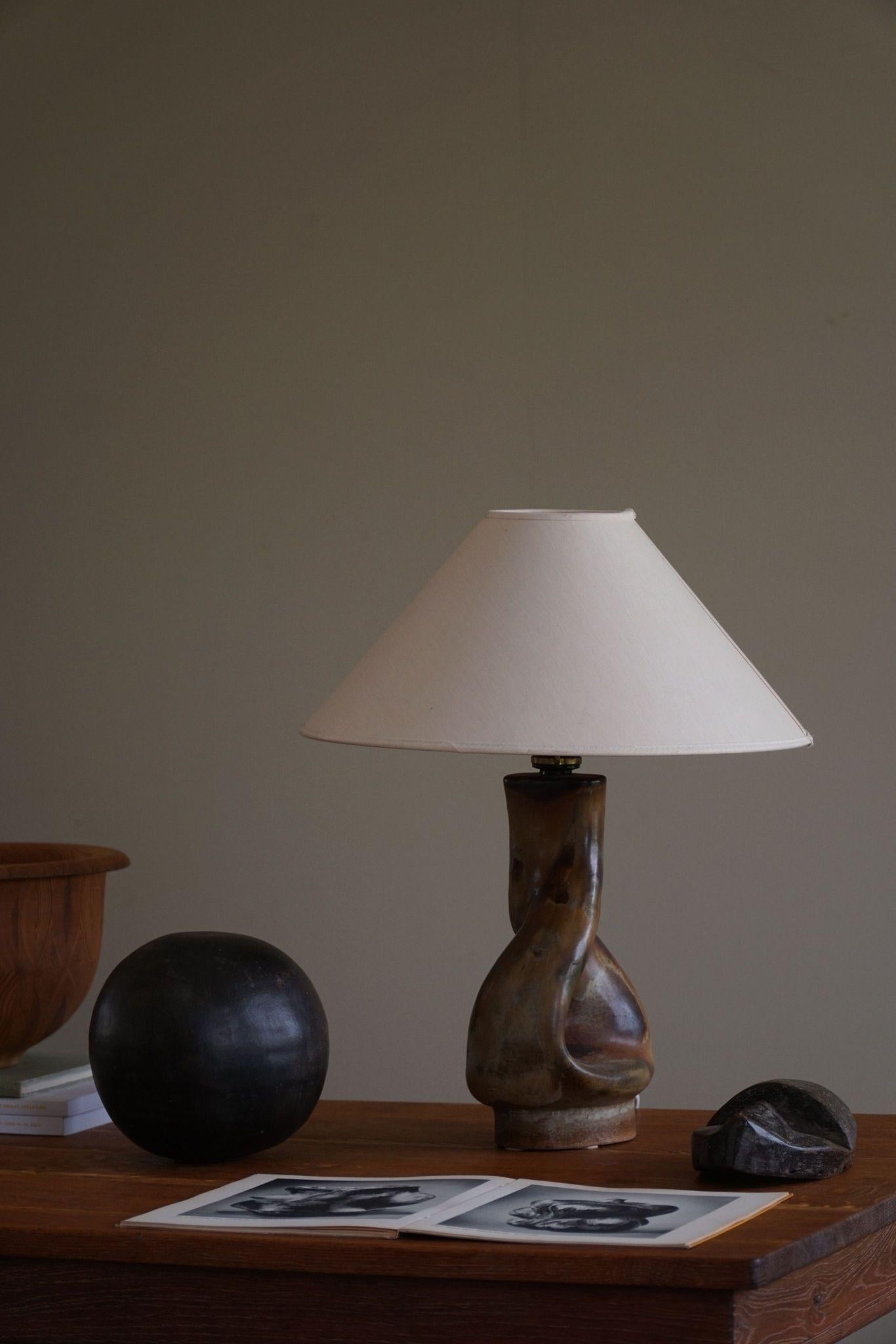 Danish Modern organic shaped stoneware table lamp. Made in various earthern / green colors. Made in the 1970s by Axella Stentøj, signed underneath. 

This item is in a great vintage condition. This beautiful and calm lighting complements many types
