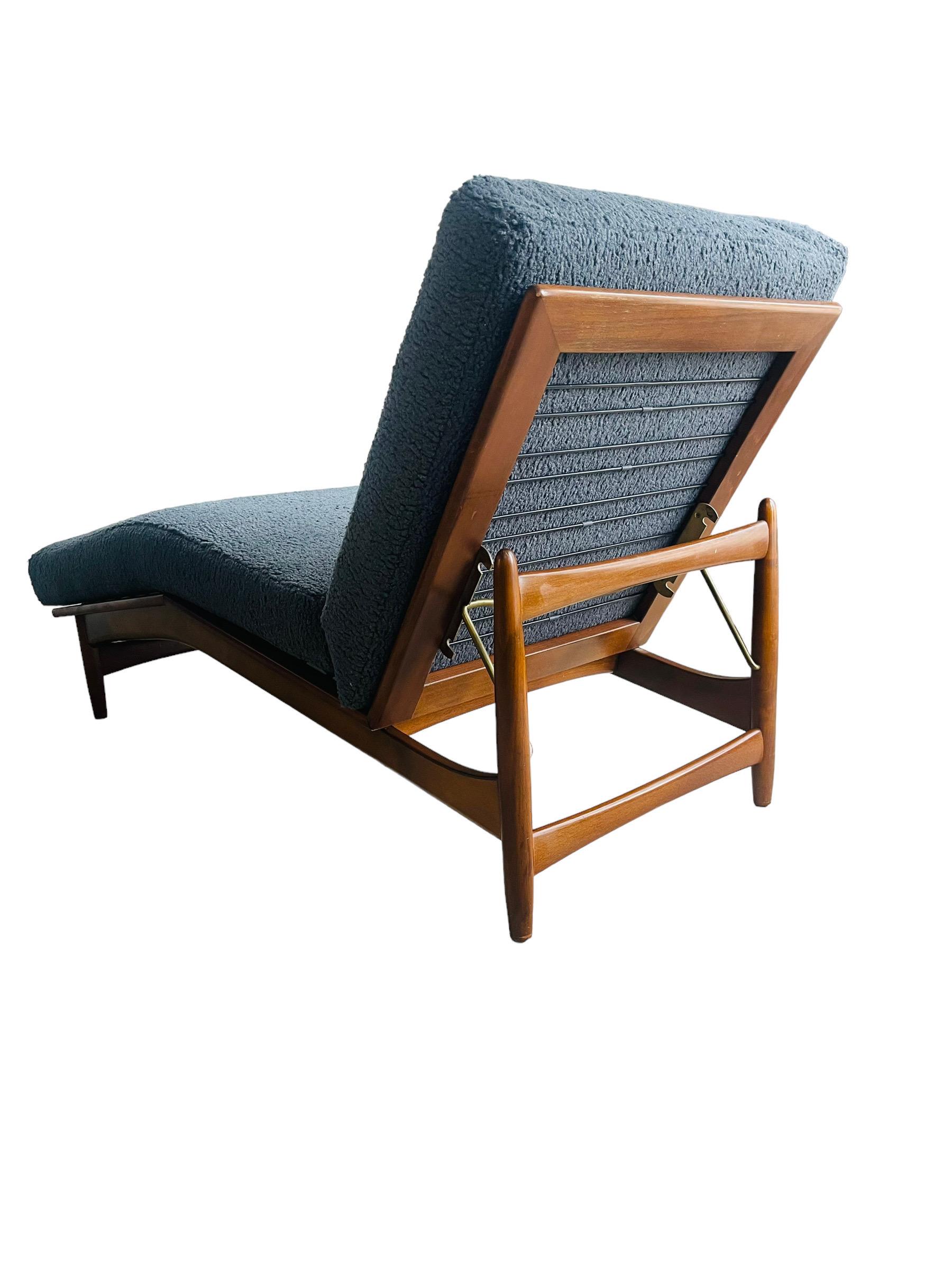 Introducing the 1950s midcentury Danish modern chaise lounge chair, designed by the legendary IB Kofod Larsen for Selig. This unique piece boasts a beautiful walnut frame and has been thoughtfully reupholstered with deep blue bouclé fabric, offering