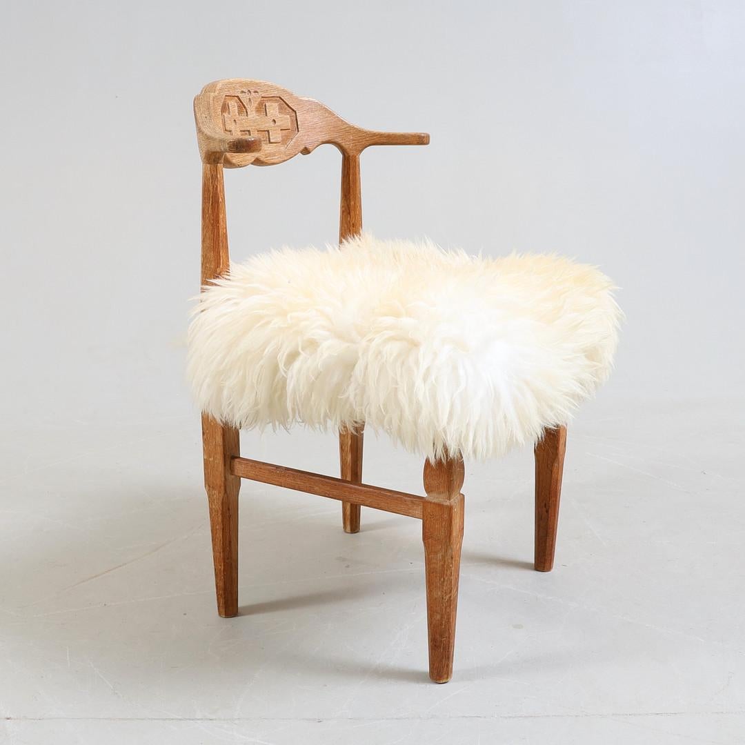 Silla escultural de roble blanco nórdico y piel de oveja con motivo de cruz tallada a mano, obra del arquitecto danés Henning Kjærnulf y fabricada por EG Møbler, Dinamarca, en la década de 1960-1970. Quedaría genial en un chalet como escritorio o