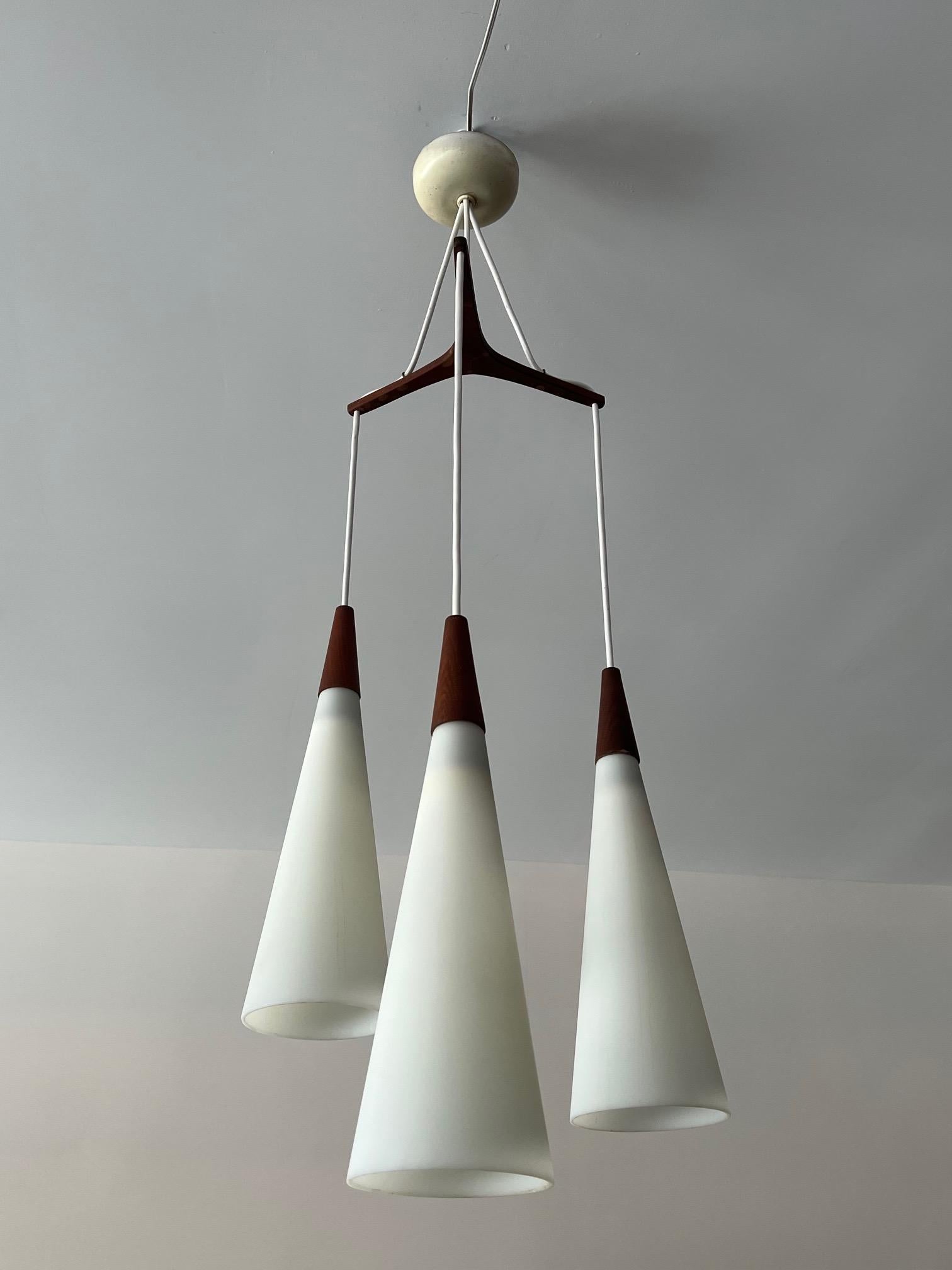 Un elegante lampadario danese degli anni '60 circa. Teak e vetro opalino, eleganti paralumi in vetro affusolato, ricablato.