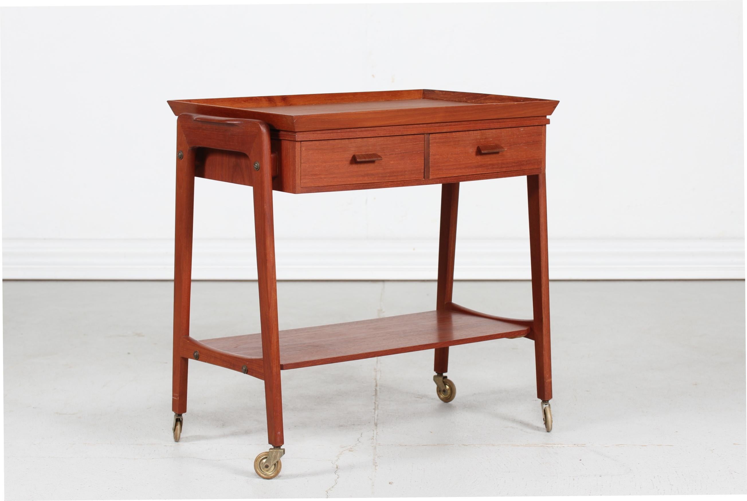 Danish modern cocktail- or serving trolley with removable butler´s tray made of teak and designed by a danish architect in the 1960s
The trolley has two drawers with dovetail joints and a bottom shelf.

Very nice vintage condition, ready for