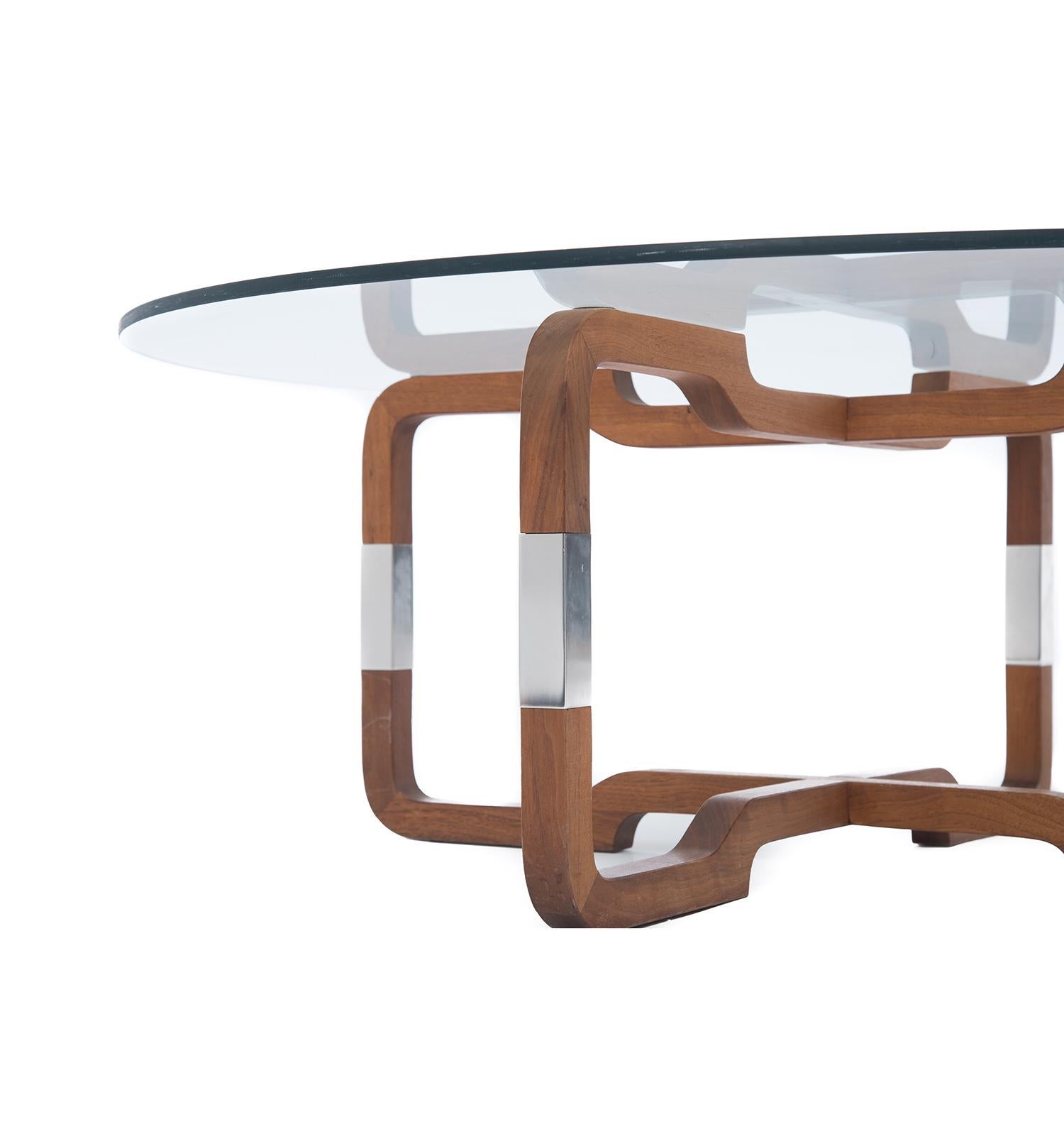 This glass top coffee table sits above a uniquely shaped teak base with chrome accents.