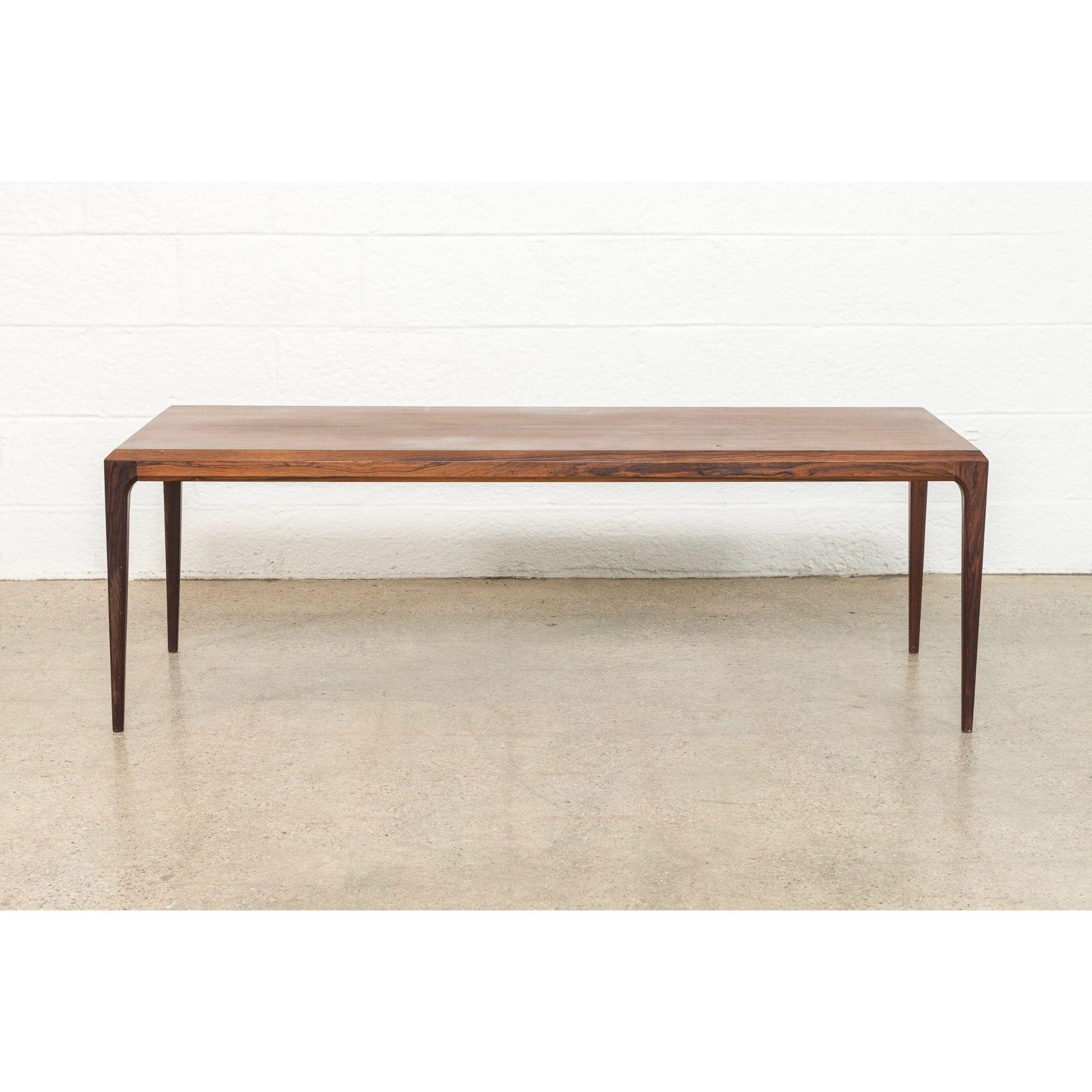 This exquisite Danish modern rosewood coffee table was designed by Johannes Andersen for CFC Silkeborg and made in Denmark circa 1960. The classic minimalist design features clean, elegant lines and the table is expertly crafted from solid rosewood