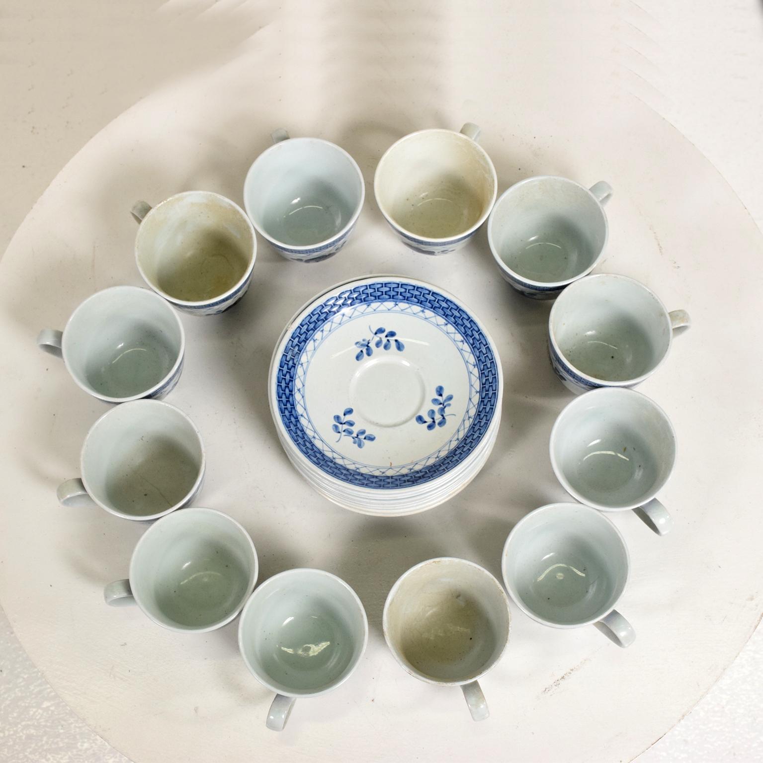 AMBIANIC offering:   
Danish Modern Coffee Tea Cup  Saucer Service Set for (12) Twelve. Delicately designed rim lattice band rose pattern in Tranquebar Blue and White Porcelain. Midcentury Modern 1960s.
Stamped underneath faded makers symbols.