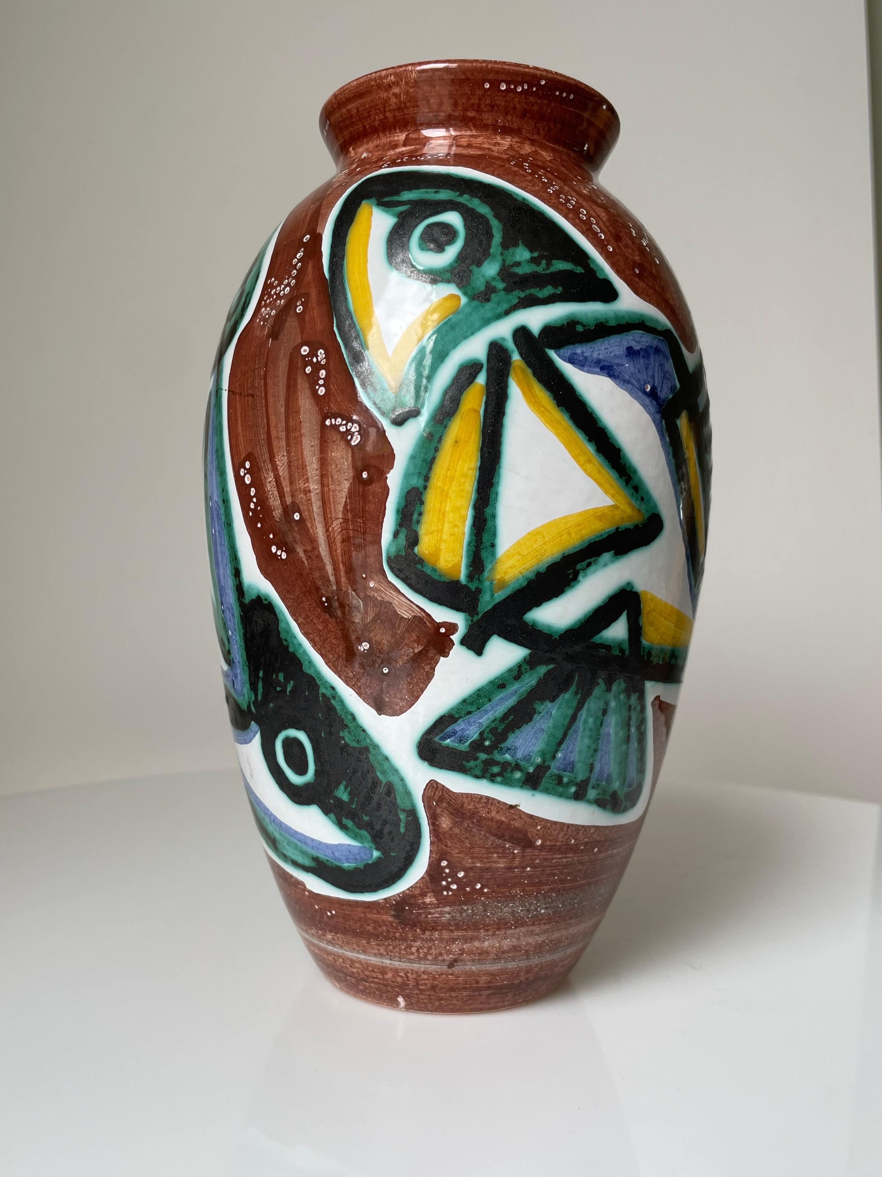 Handpainted ceramic vase manufactured in the 1960s by Johgus Keramik on the island of Bornholm. Two large colorful fish in green, yellow, lilac and black glaze on caramel brown and white base. Small white dots illustrating bubbles under water.