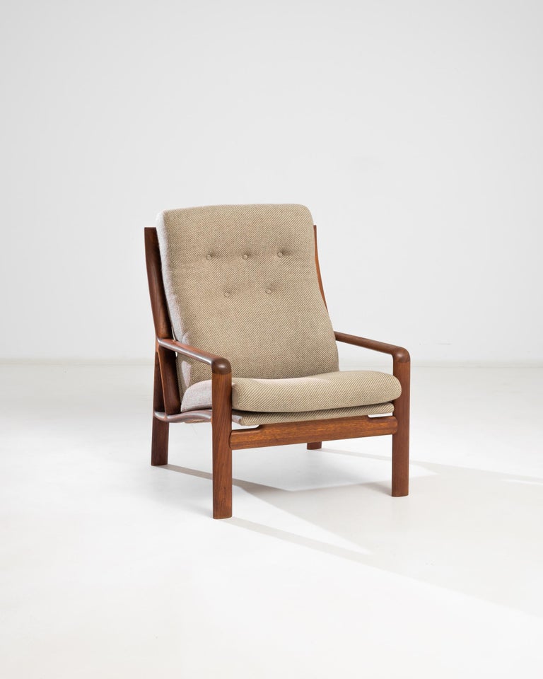 This teak armchair was made in Denmark circa 1960. Exuding the coziness of a Scandinavian home, this detailed piece is expertly crafted to highlight the beauty and comfort of natural materials. Button-tufted backs and puffy cushions upholstered in a