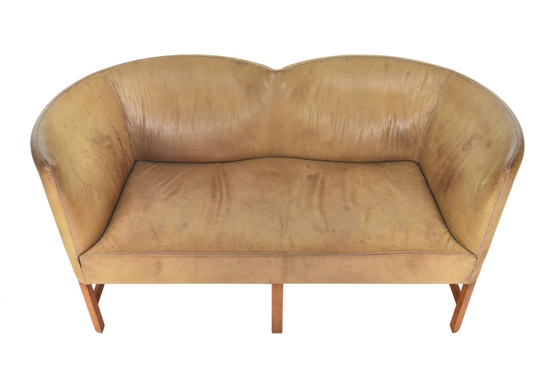 This understated Danish modern loveseat is covered in exquisitely patinated leather that only decades of time can create! With a silhouette similar to Børge Mogensen’s 2214 sofa, this high back sofa offers two converging scooped backrests. Sofa