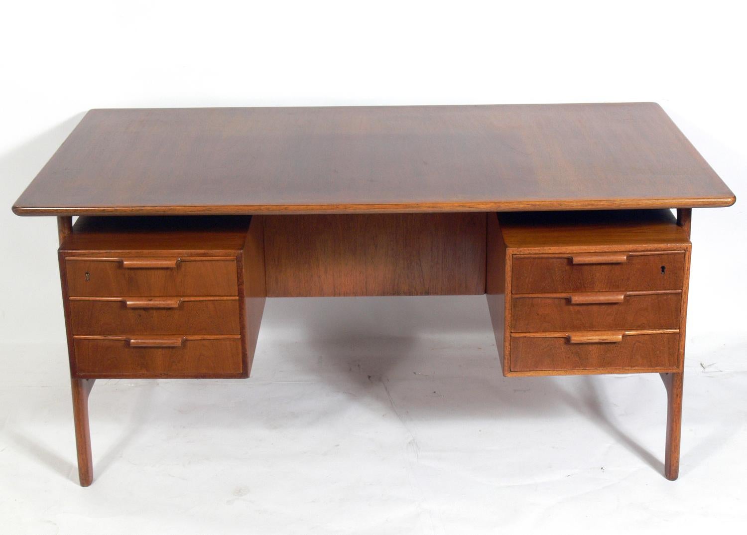 Danish modern teak fesk designed by Gunni Oman for Omann Juns Møbelfabrik, Denmark, circa 1960s. Impressed signature underneath. It is a versatile size and can be floated in a room or used as a partners desk, as it is finished on the back side. It
