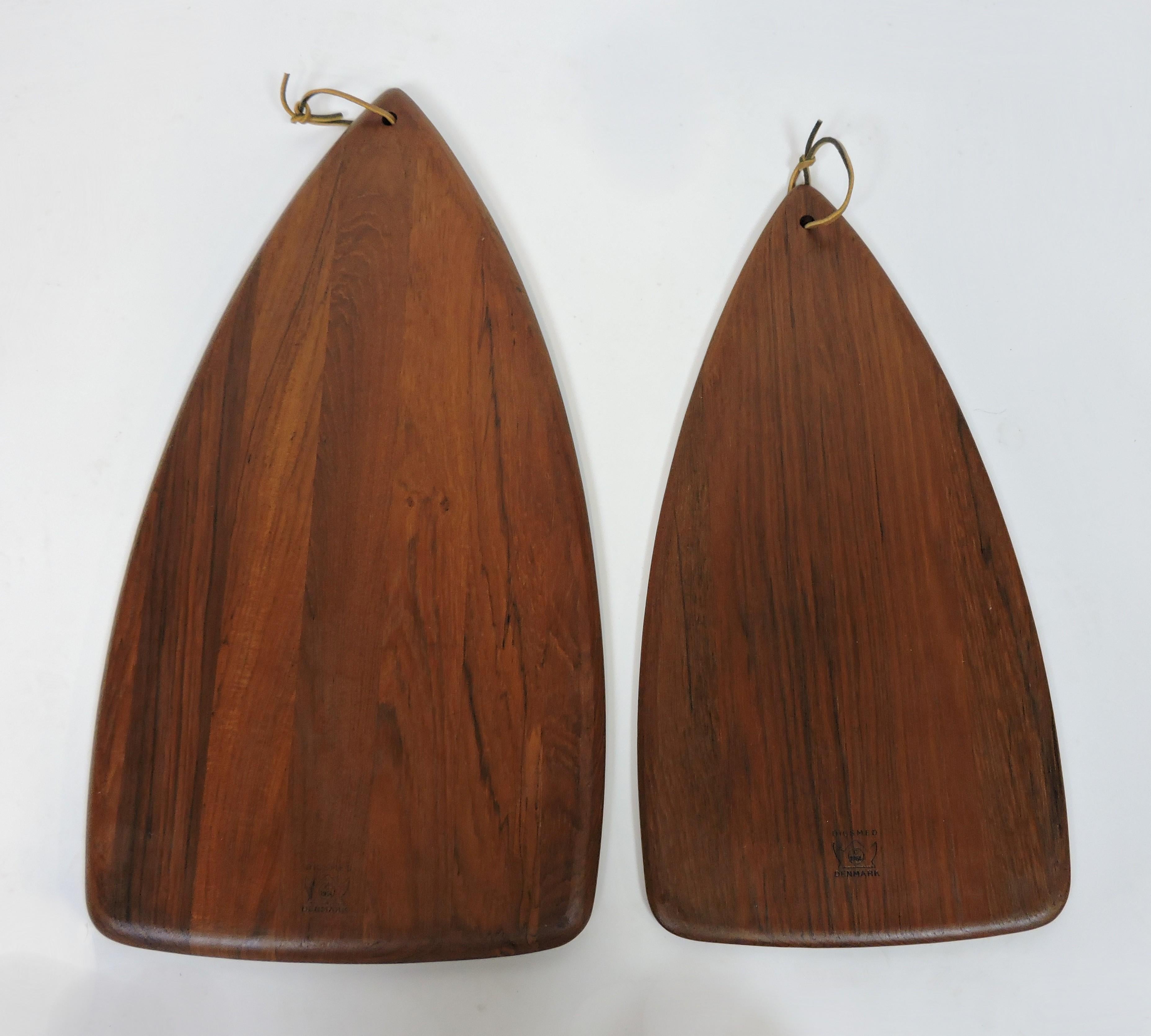 Beautiful set of two Digsmed of Denmark teak cutting boards. The larger one is 22 inches long and the smaller is 18.5 inches long. They have a triangular shape with inset magnets to hold a knife and stack together neatly for storage.