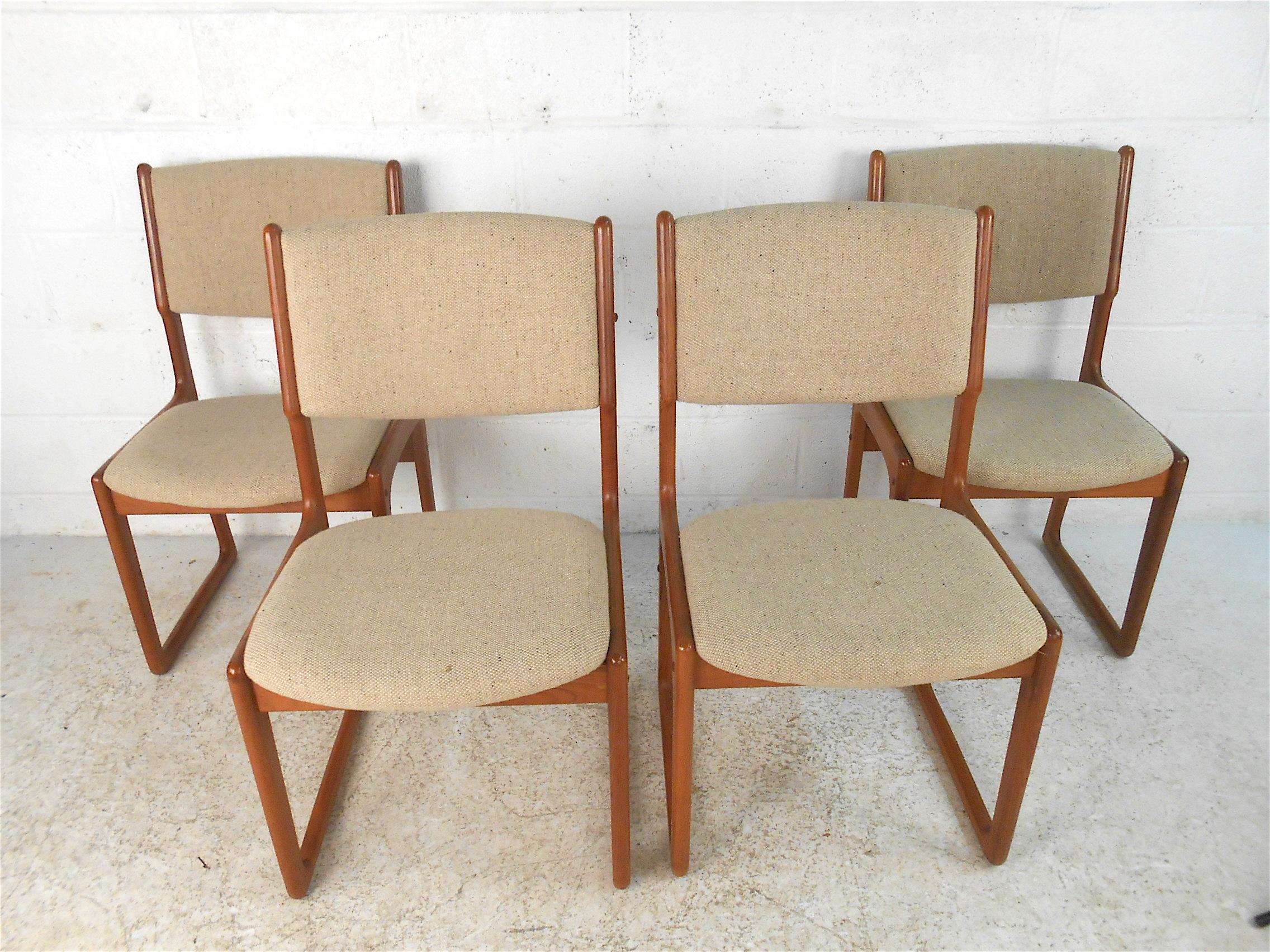 Stylish set of 4 Danish modern dining chairs by Benny Linden. Sturdily constructed with handsome joinery showcased on the frames, covered in a vintage beige upholstery. Sled legs and a stretcher across the back of the frame gives these chairs an