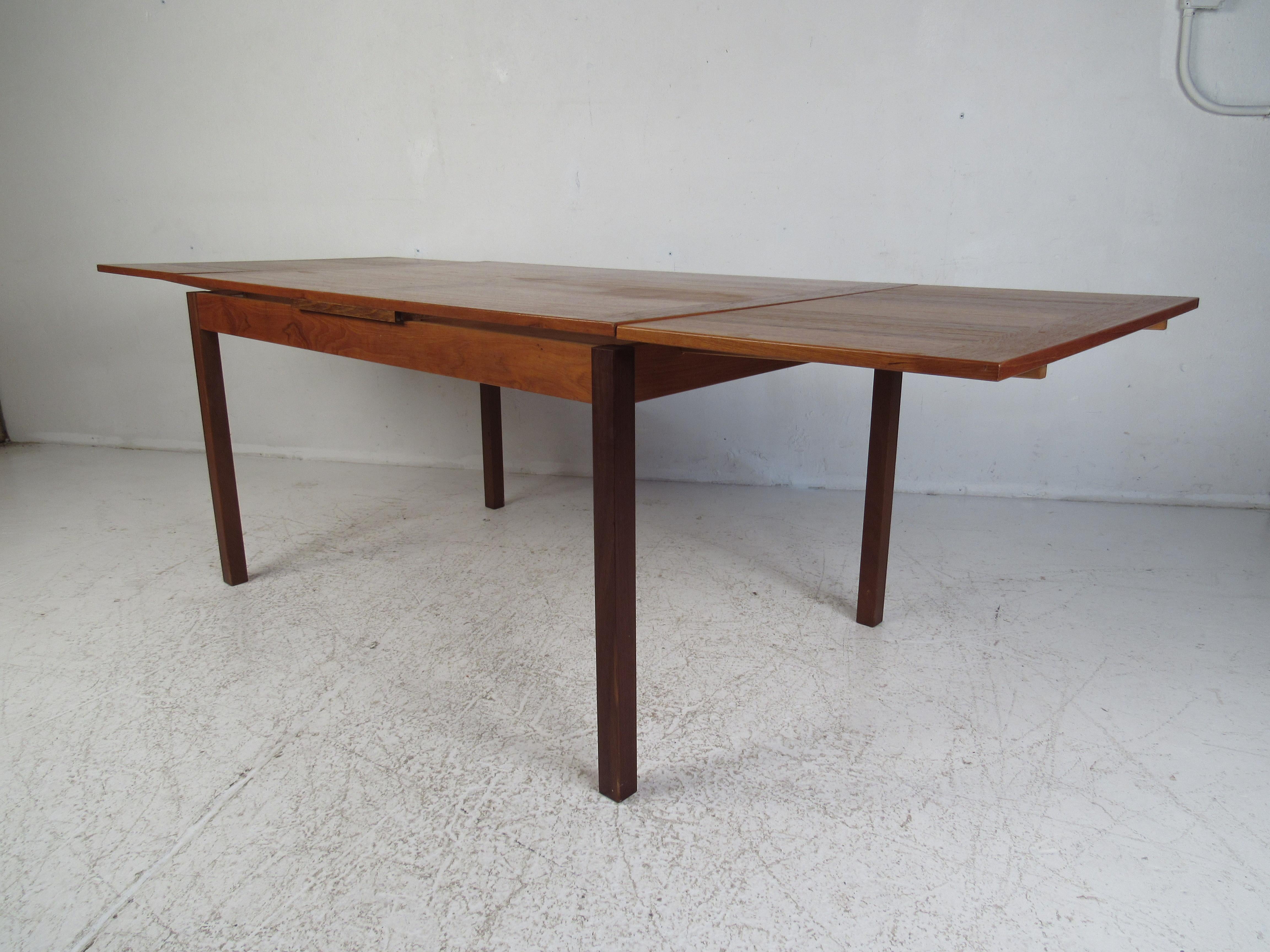 This stunning Mid-Century Modern dining table boasts a unique butcher block style wood grain on each of the leaves that complements the center. A convenient draw leaf design that expands from 53.25 inches wide all the way to 92.75 inches wide once