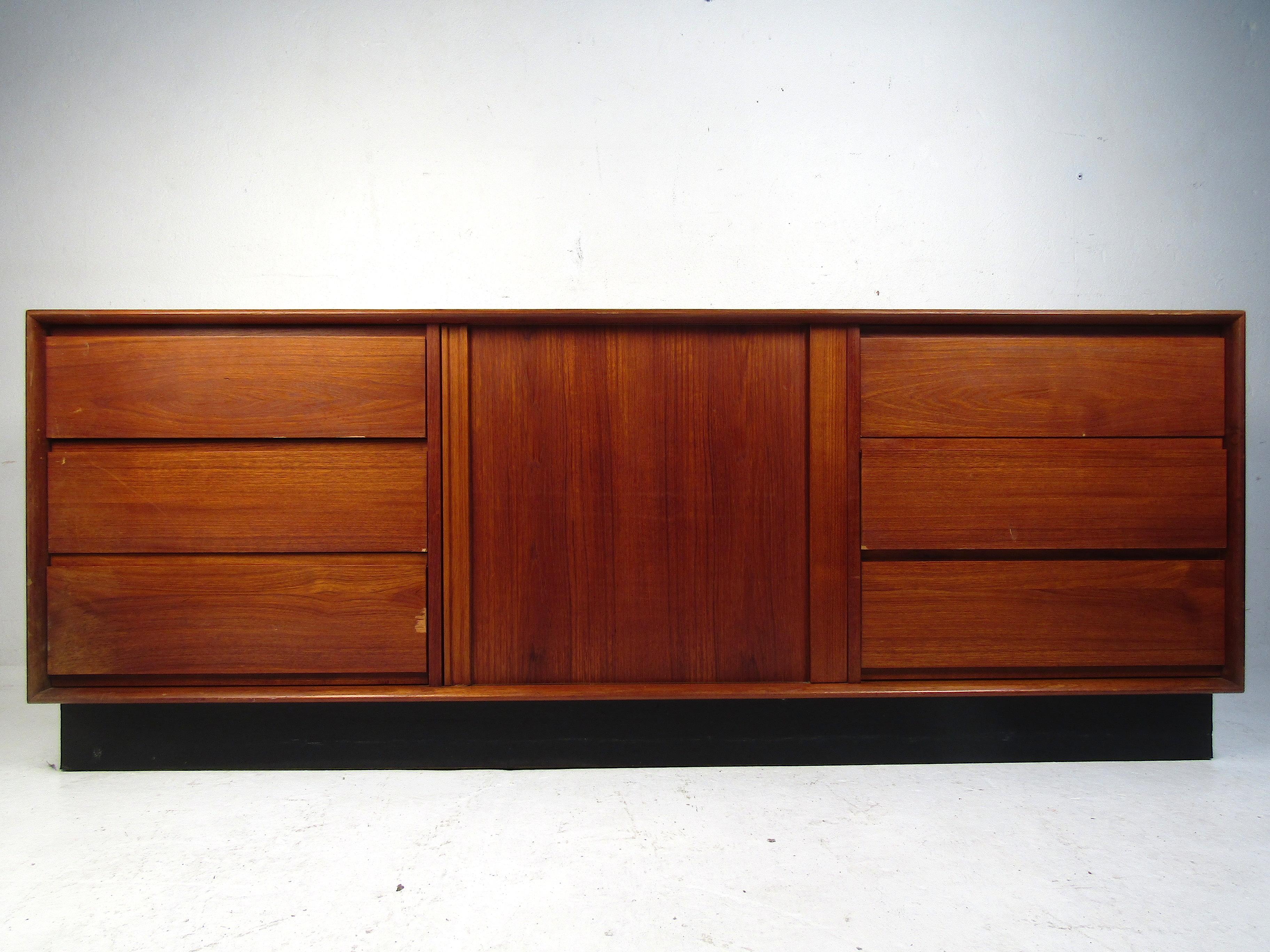 Stylish Danish Mid-Century Modern dresser by Art Furn. Good-looking teak veneer throughout, with six dovetail-jointed drawers on each flank of the case piece, complemented by cabinet space concealed by a tambour door in the center. Black skirt base.