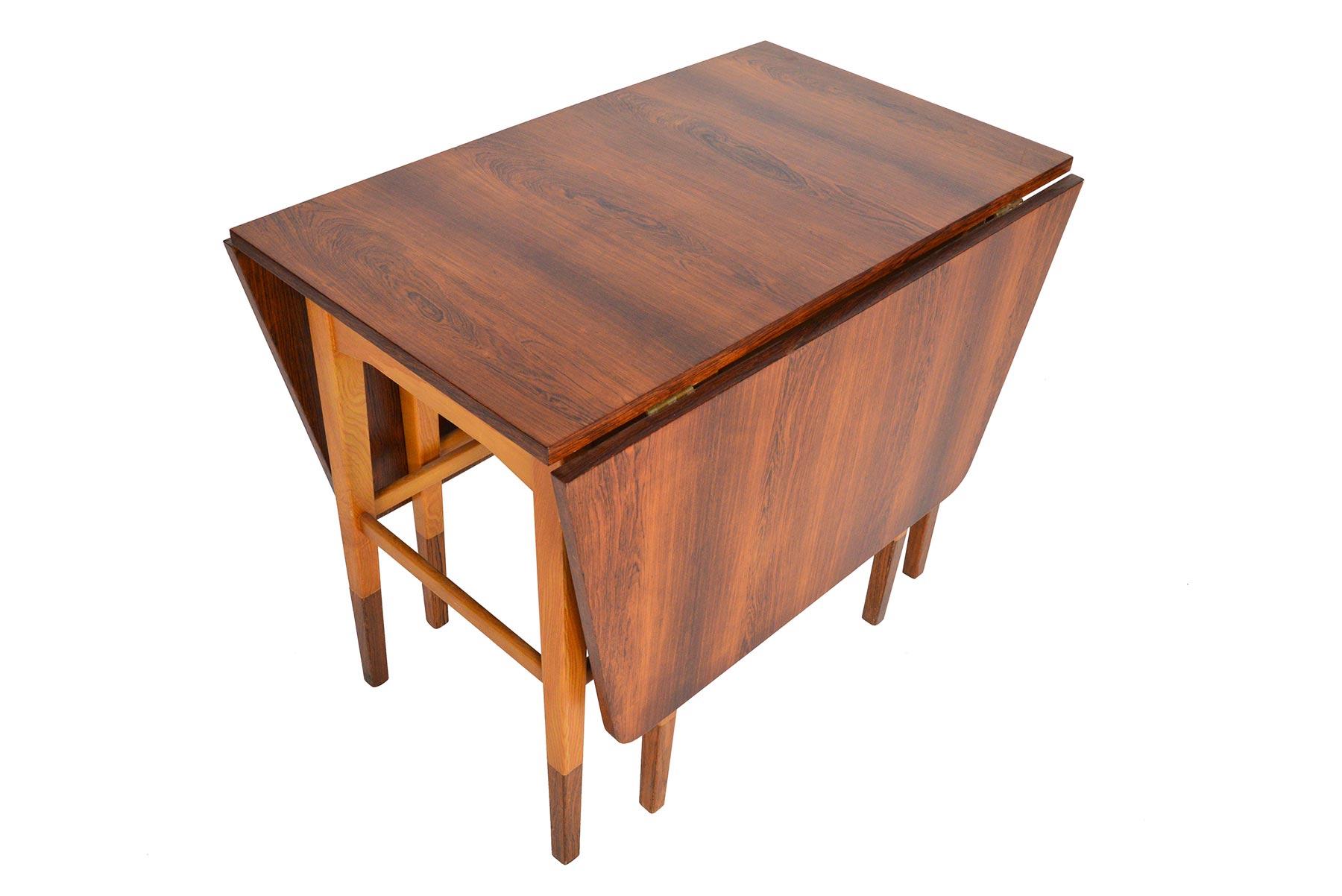 This beautifully crafted Danish modern drop leaf console table is constructed in Brazilian rosewood and solid oak. The table expands with the help of two expanding leg bases that support the leaves. Tapered oak legs are capped in rosewood. In