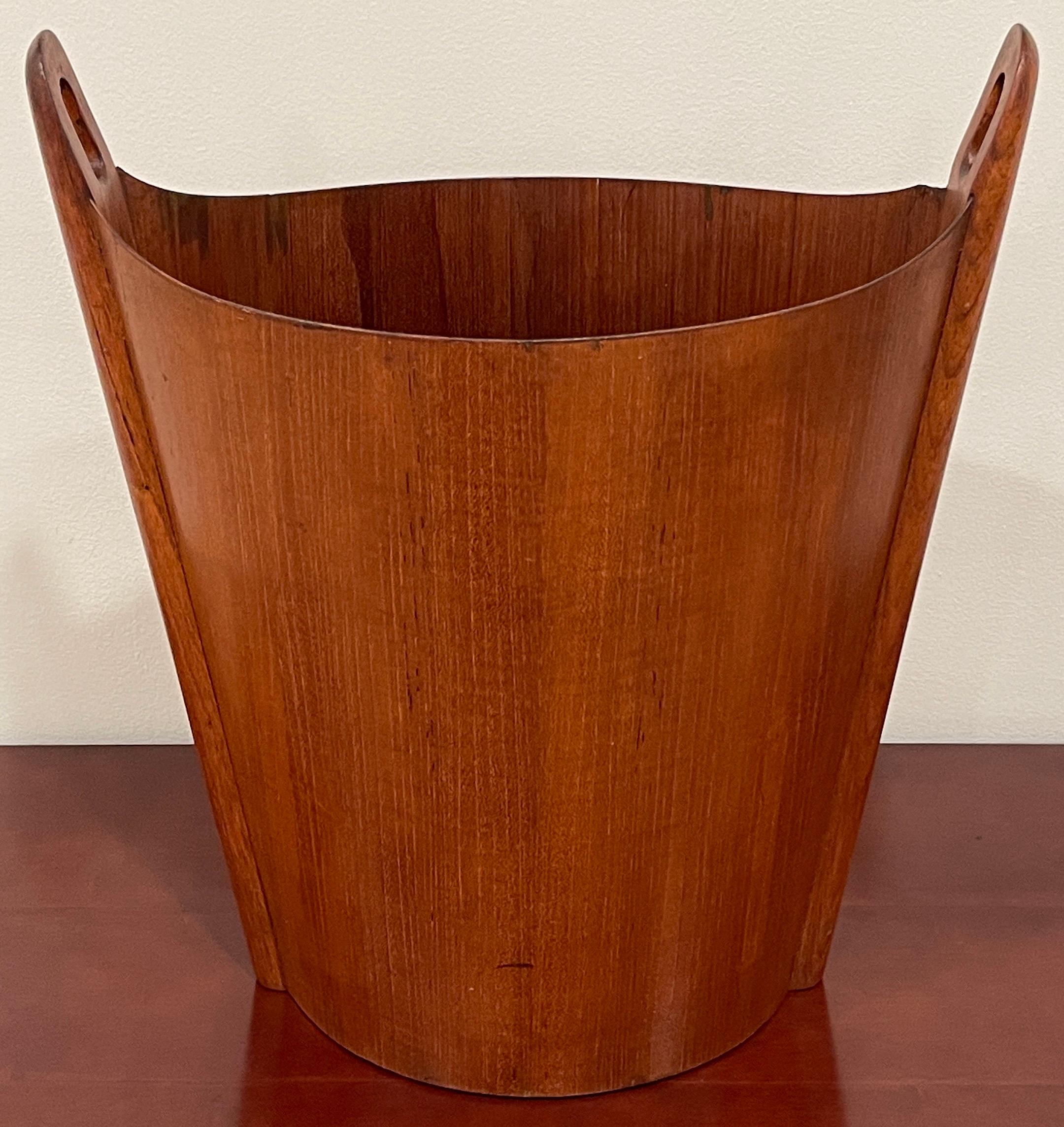 Danish Modern Einar Barnes for P.S. Heggen teak wastepaper basket 
A fine example of sculpted teak waste paper basket designed by Einar Barnes and manufactured by P. S. Heggen in an oval shape with loops at both ends supported by tapering columns,