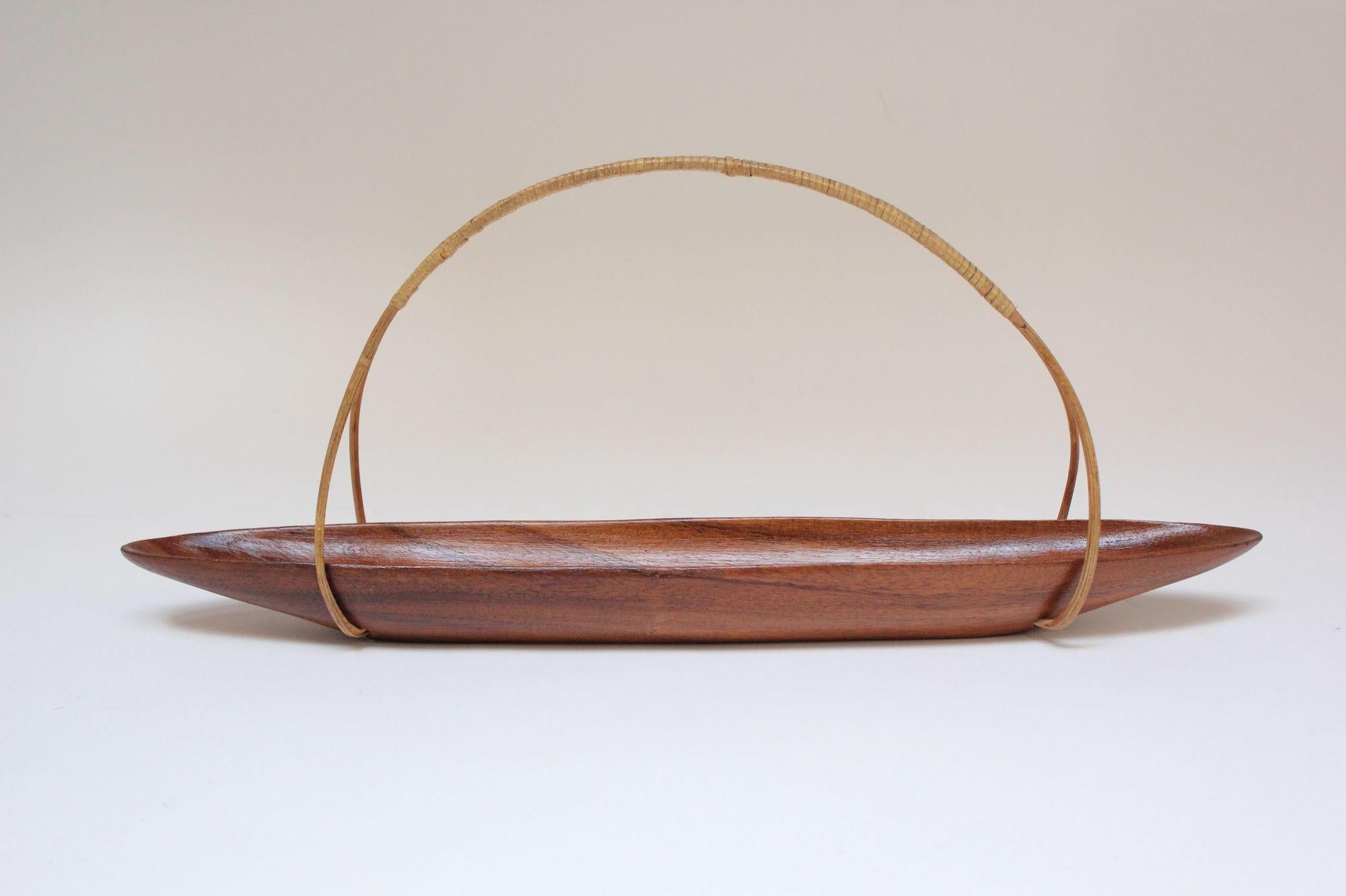 Stylish boat-shaped decorative bowl in teak with hooped, wicker handle (ca. 1960s, Denmark).
Narrow, long shape ideal for displaying lemons, limes or other similarly shaped/sized items.
Branded 