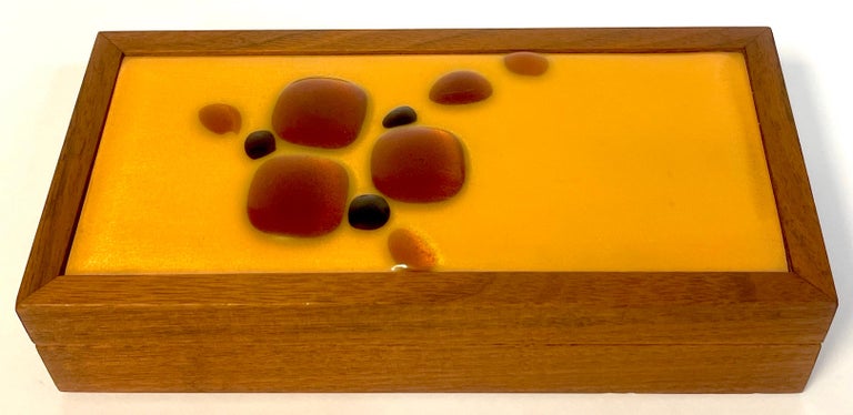 Danish modern enameled abstract teak table box
Of rectangular form, the top with inset enamel on copper with jewel-like decoration, the lower case with divided interior with two 4-Inch wide x 3-inch deep sections. Signed with 'AD'Monogram on the
