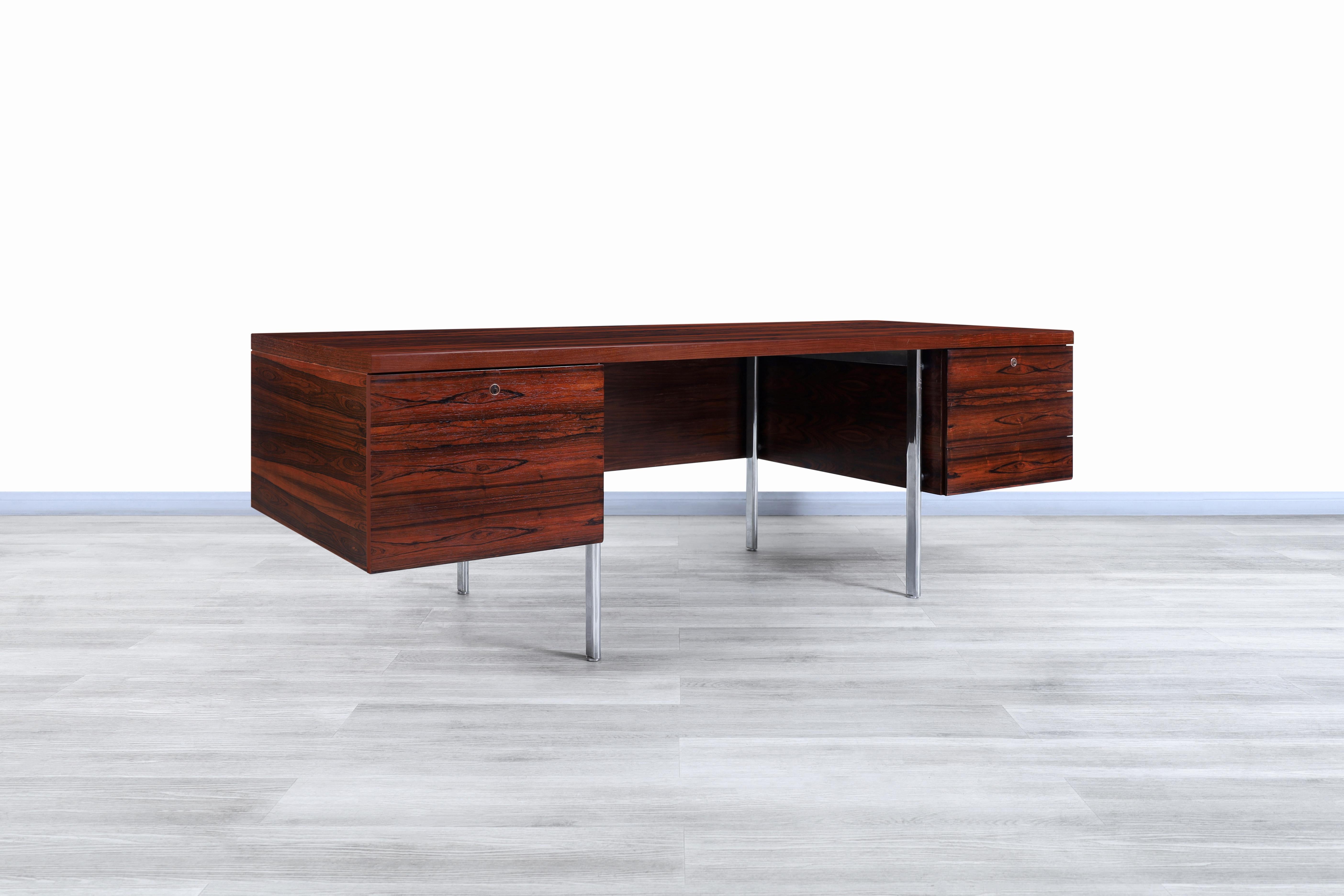 Wonderful Danish modern executive rosewood desk designed and manufactured in Denmark, circa 1960s. This desk has a very particular design that focuses on offering a large workspace and versatility for the user. The desk has been built from Brazilian