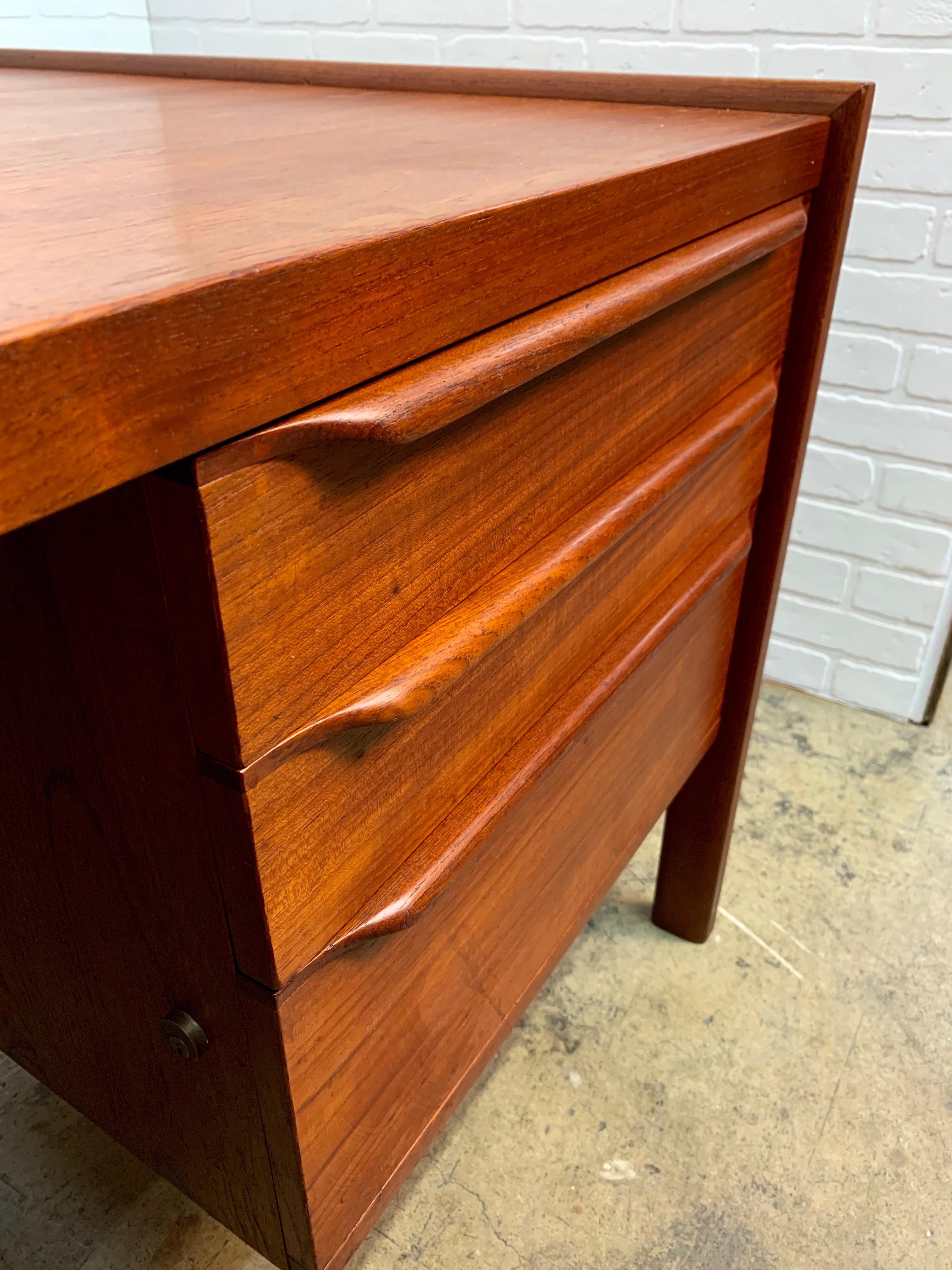 Very large executive teak Danish modern desk with sculptural drawer pulls and file drawer.