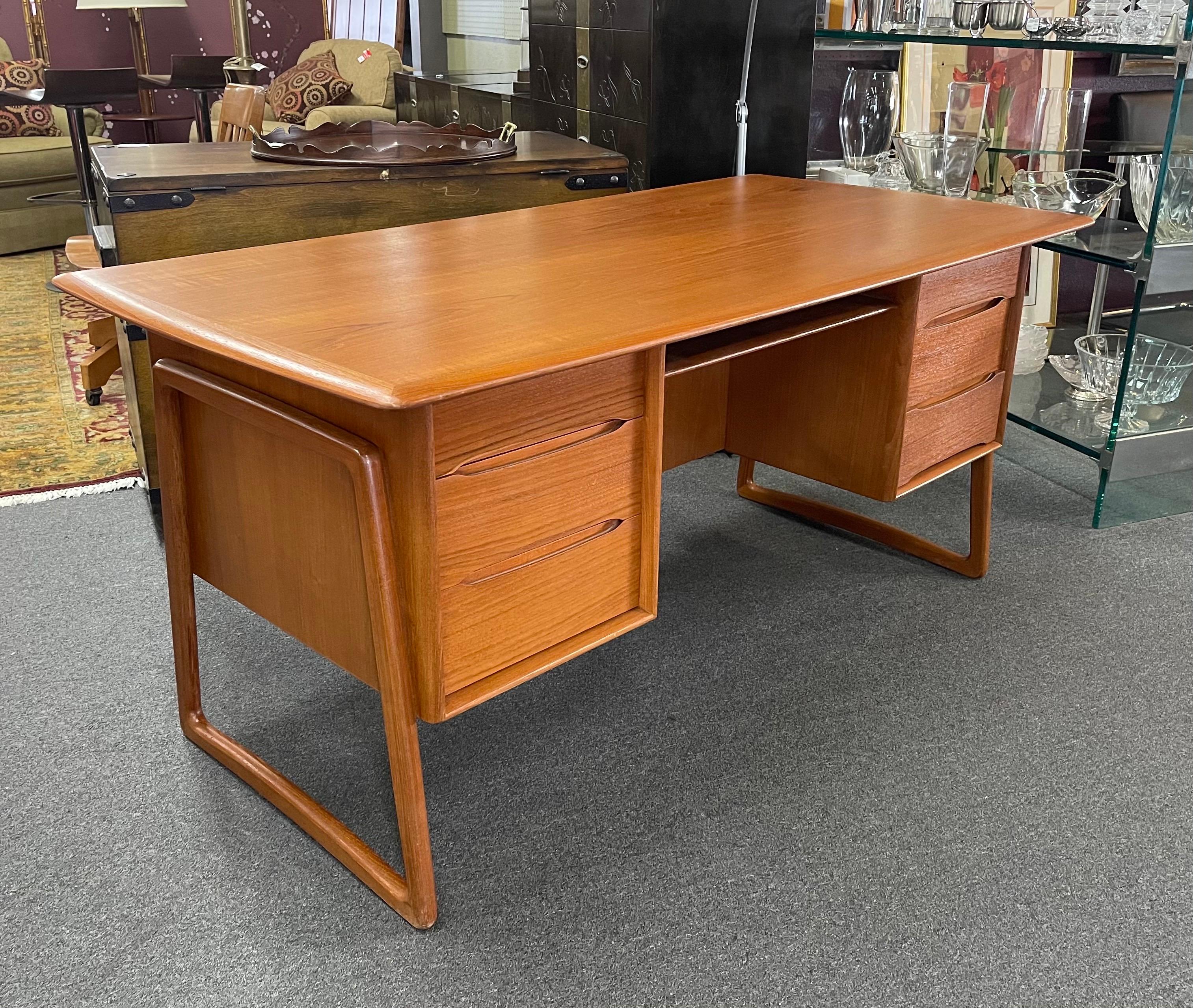Iconic Danish modern executive desk in teak by Svend Aage Madsen for Sigurd Hansen, circa 1950s. The front features six dove tailed storage drawers while the backside shows an open and fully finished compartment offering plenty of book storage and