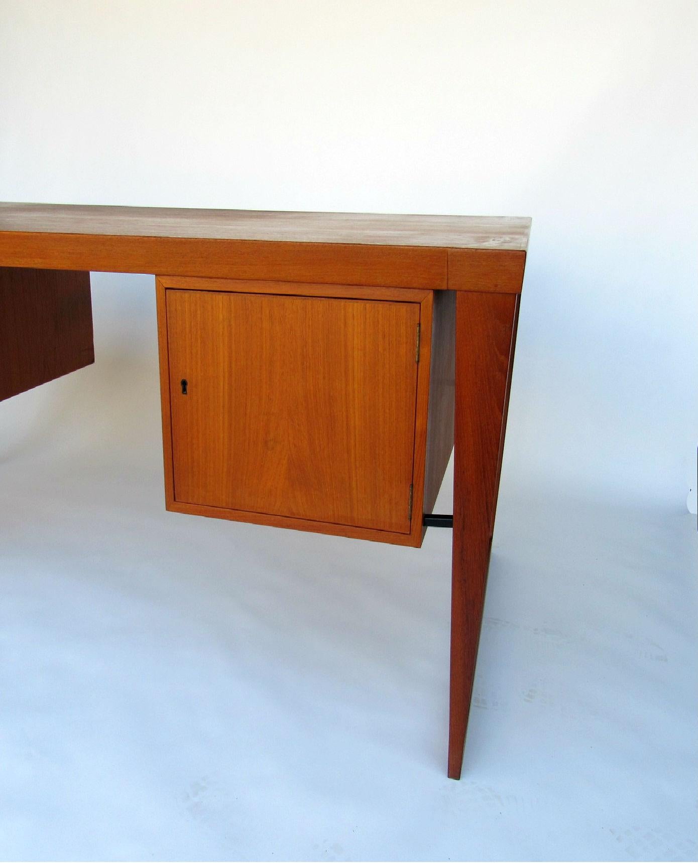 Kai Kristiansen Desk for FM Møbler.  Executive desk in teak with drawers on the backside and locking storage cabinets in the front. A sleek and functional superb example of Danish Modern design that provides ample storage, surface space, and