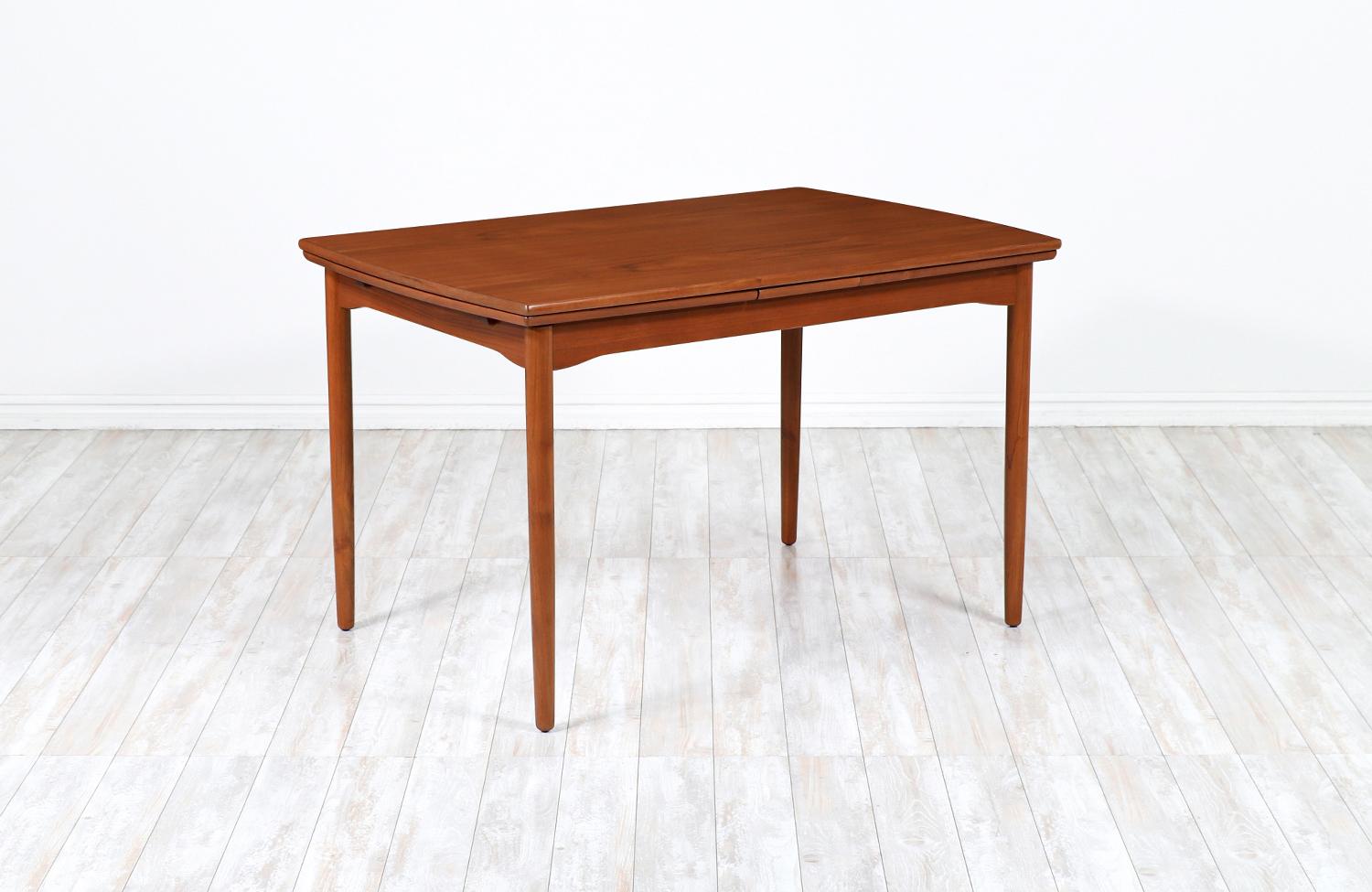 Beautiful draw-leaf dining table designed and manufactured in Denmark circa 1950s. This elegant and classic Danish design features a teak wood top supported by four solid taper legs creating a mixture of clean, modern lines and a gorgeous teak wood