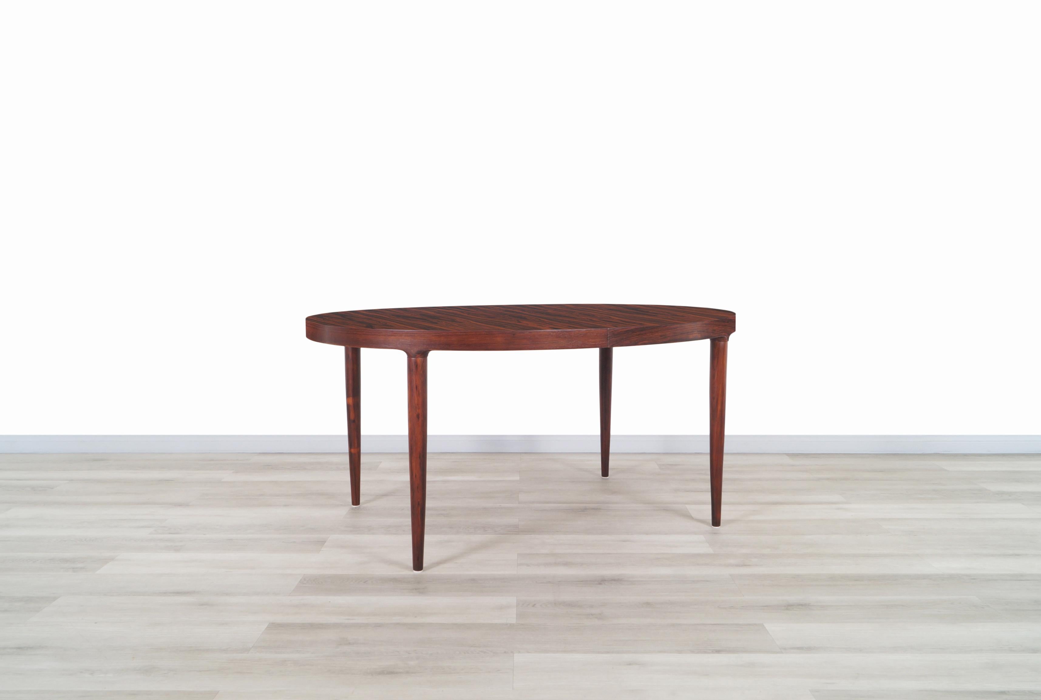 Amazing Danish modern expanding rosewood dining table manufactured by Moreddi in Denmark, circa 1960s. This wonderful oval table is distinguished by its Brazilian rosewood grain that shows across the entire top and sits on four solid rosewood