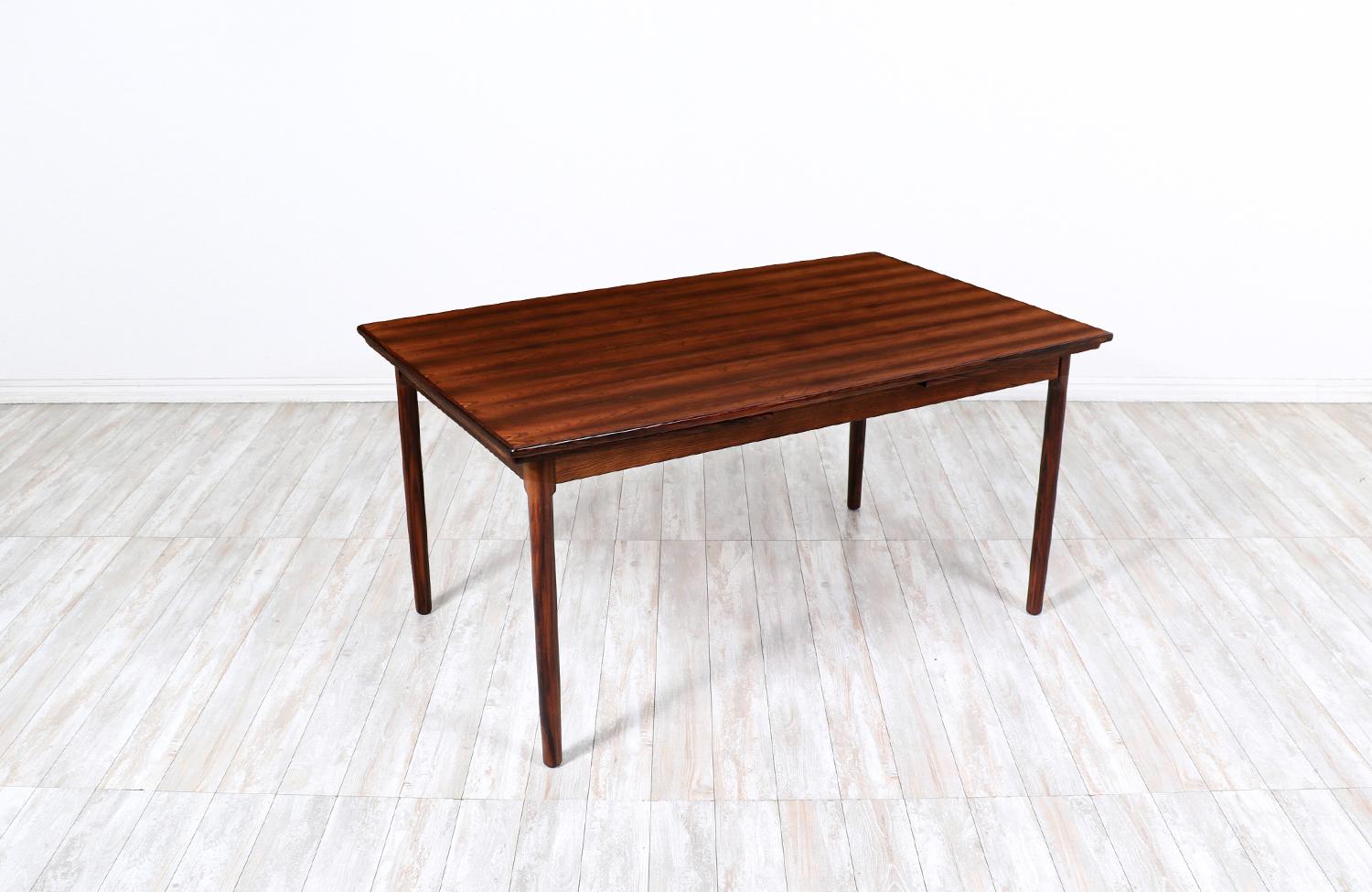 Adorable Danish Modern Rosewood dining table designed by Randers Mobelfabrik and manufactured by Randers Mobelfabrik in Denmark circa 1960s. Made from a solid Brazilian Rosewood base, this exemplary Danish design features two draw leaves that store