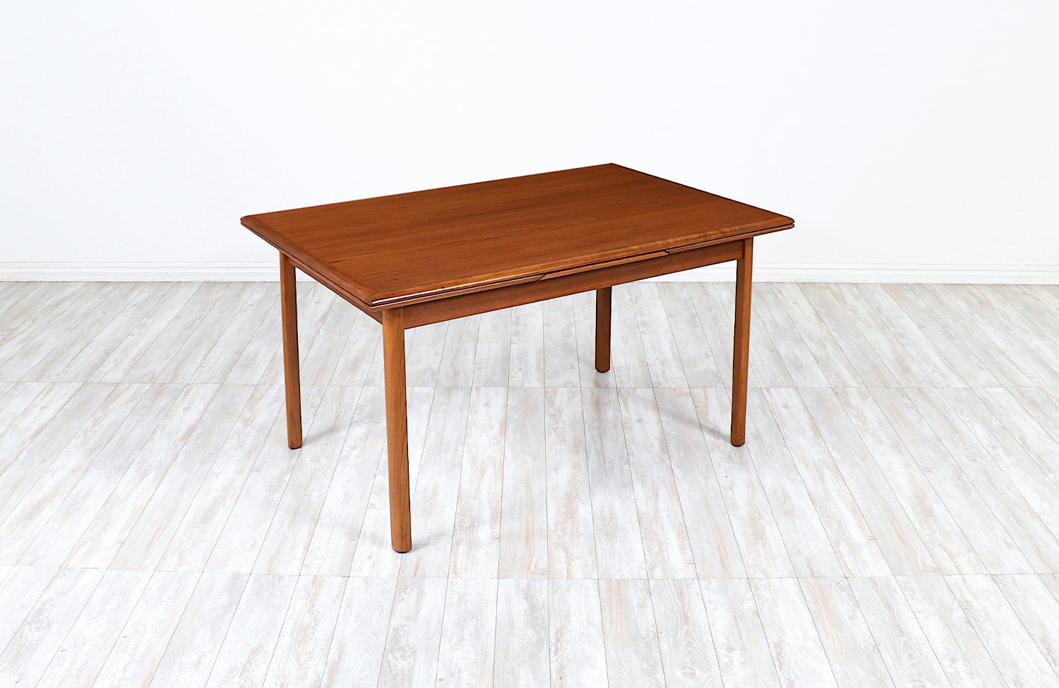 Adorable Danish Modern teak dining table manufactured and designed in Denmark circa 1960s. Made from a solid teak wood base, this exemplary Mid-Century design features two draw leaves that store inconspicuously underneath the table top. This design