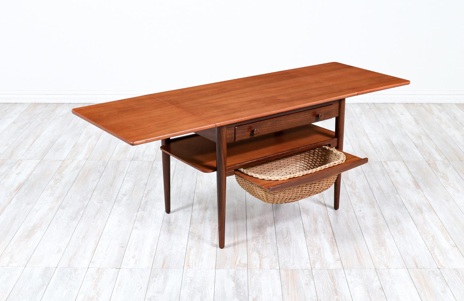 Expanding teak sewing table designed by Danica Mobler in Denmark circa 1960’s. This Danish modern design features an teak frame, a pull-out wicker basket and a sectioned drawer for sewing materials. The table top and bottom shelf are made of teak