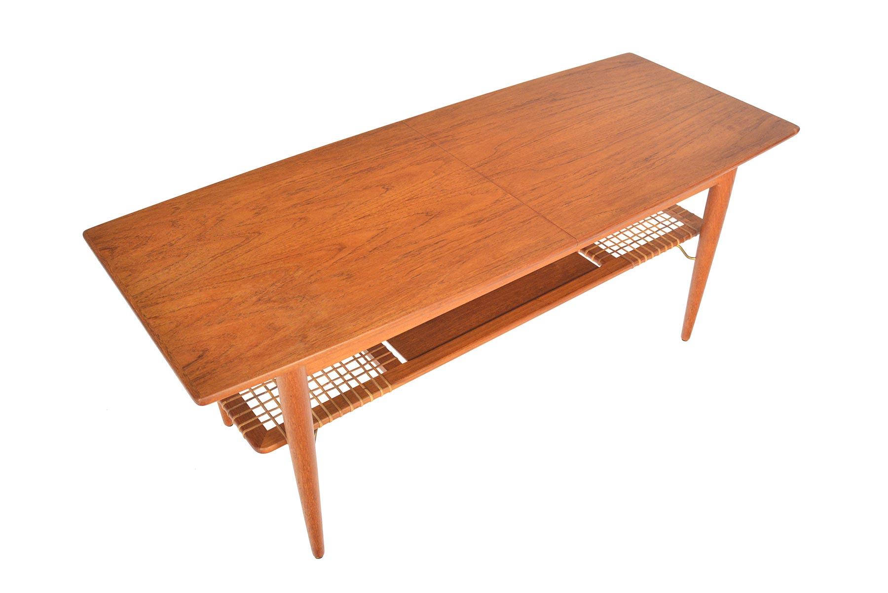 This Danish modern midcentury surfboard coffee table in teak is full of surprises! Table slides apart to reveal divided storage. This piece offers a black painted leaf to extend the length of the table and is perfect for serving! An original cane