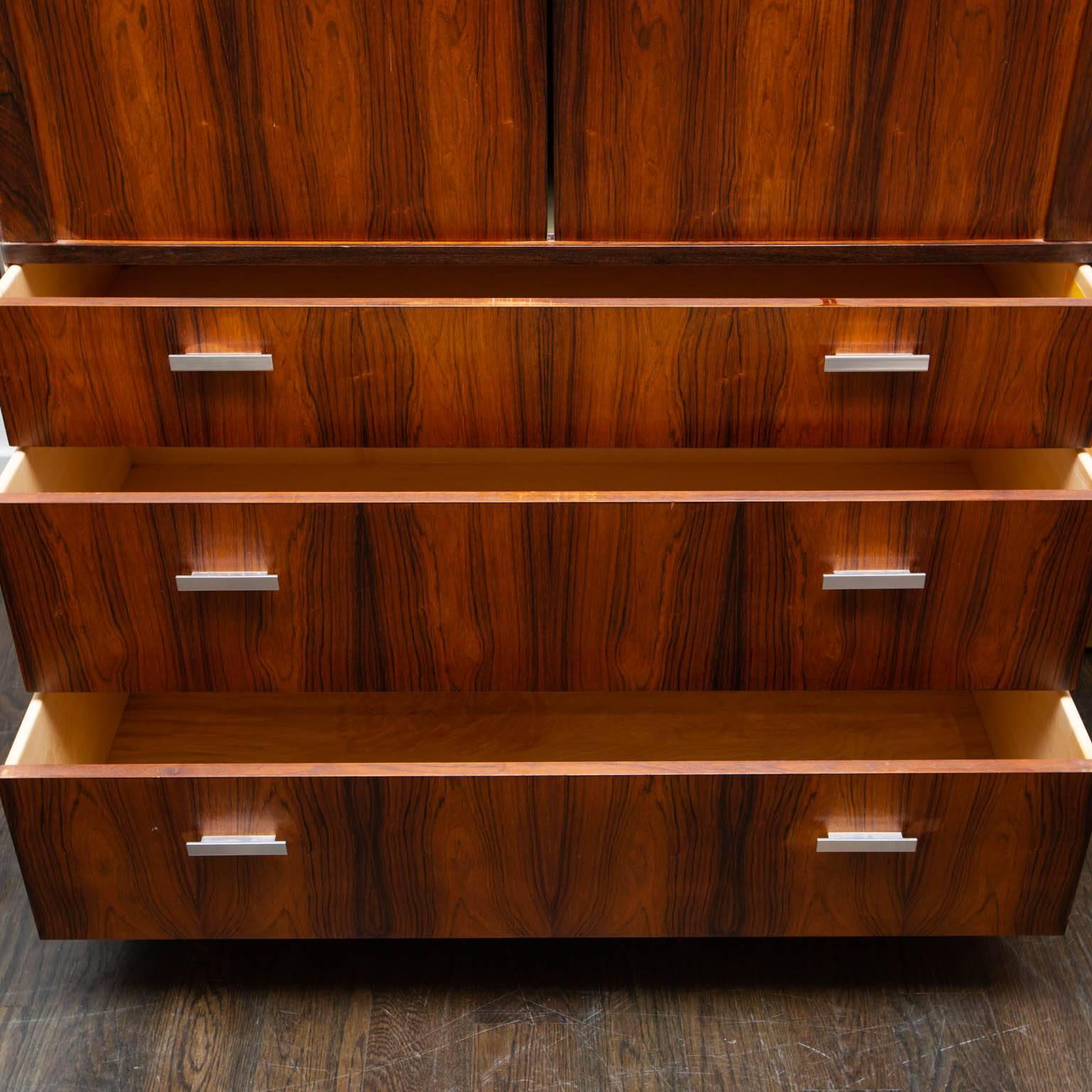 Made by Falster of Denmark. This chest features classic Danish-designed tambour doors that open to reveal nine birch wood drawers and a couple of shelves. These particular rosewood pieces by Falster were sold at Maurice Villency in New York and