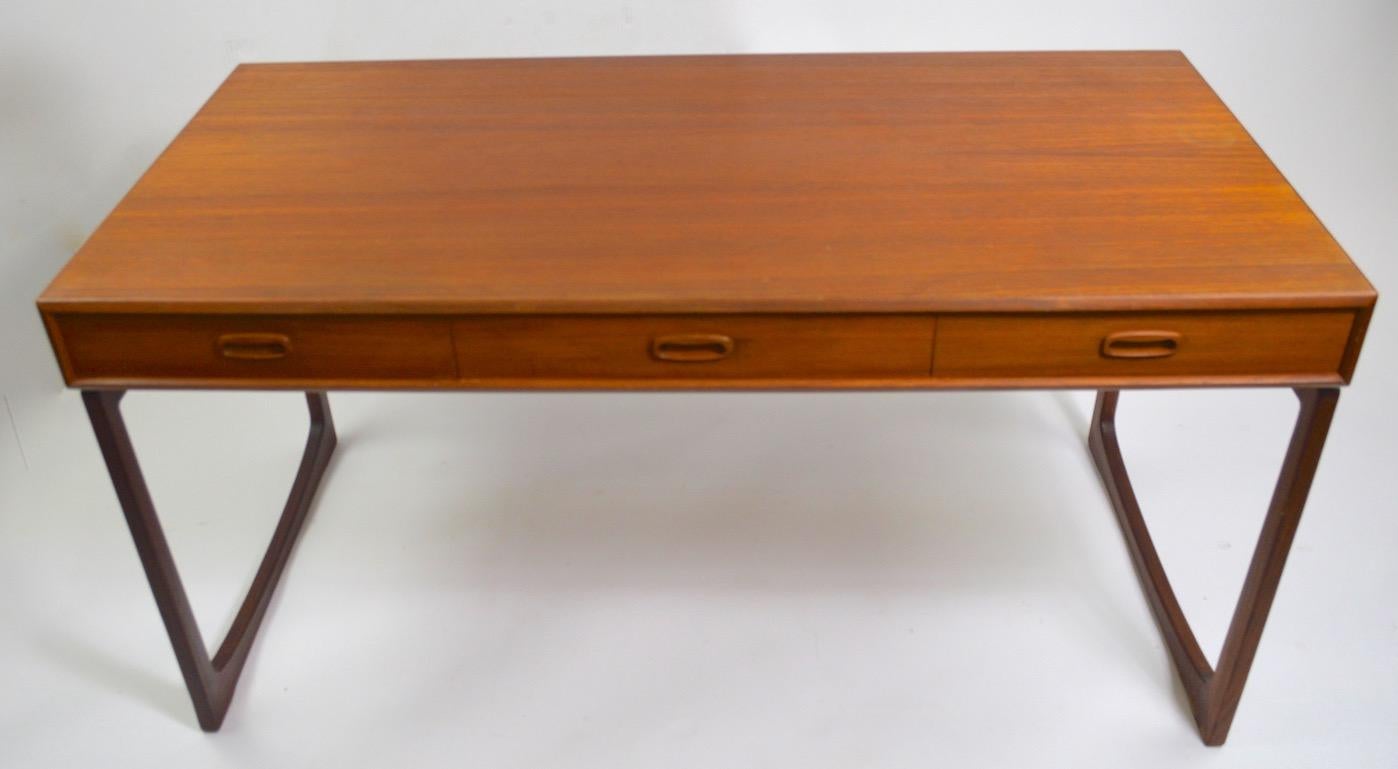 Stylish platform desk, with storage drawers, a teak top and rosewood legs. This desk features three drawers and a nice large top for your work surface. This desk displays design and construction elements found in G Plan furniture, however it is