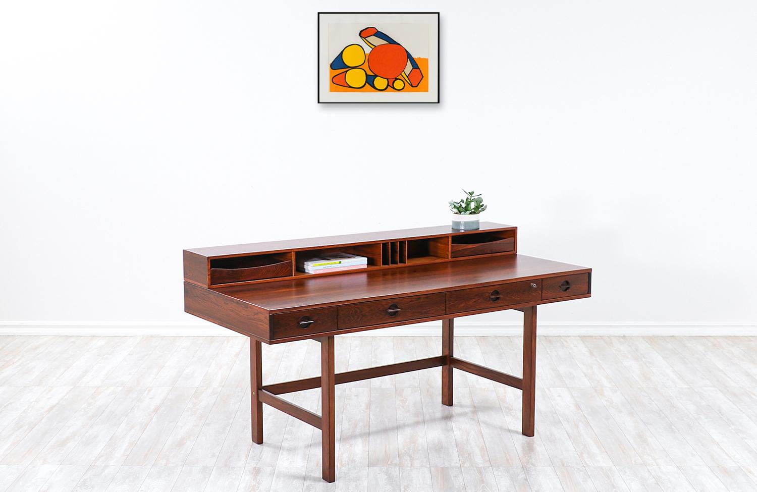 Spectacular rosewood desk designed and crafted by Peter Løvig Nielsen in Denmark, circa 1972. Its ingenious design makes it versatile in accommodating two-persons on each side by simply flipping the top shelf and having the top removable drawers