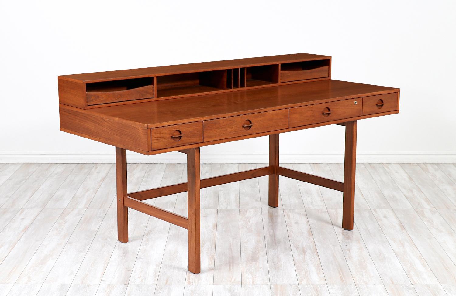 Spectacular teak desk designed and crafted by Peter Løvig Nielsen in Denmark circa 1970's. Its ingenious design makes it versatile in accommodating two-persons on each side by simply flipping the top shelf and having the top removable drawers