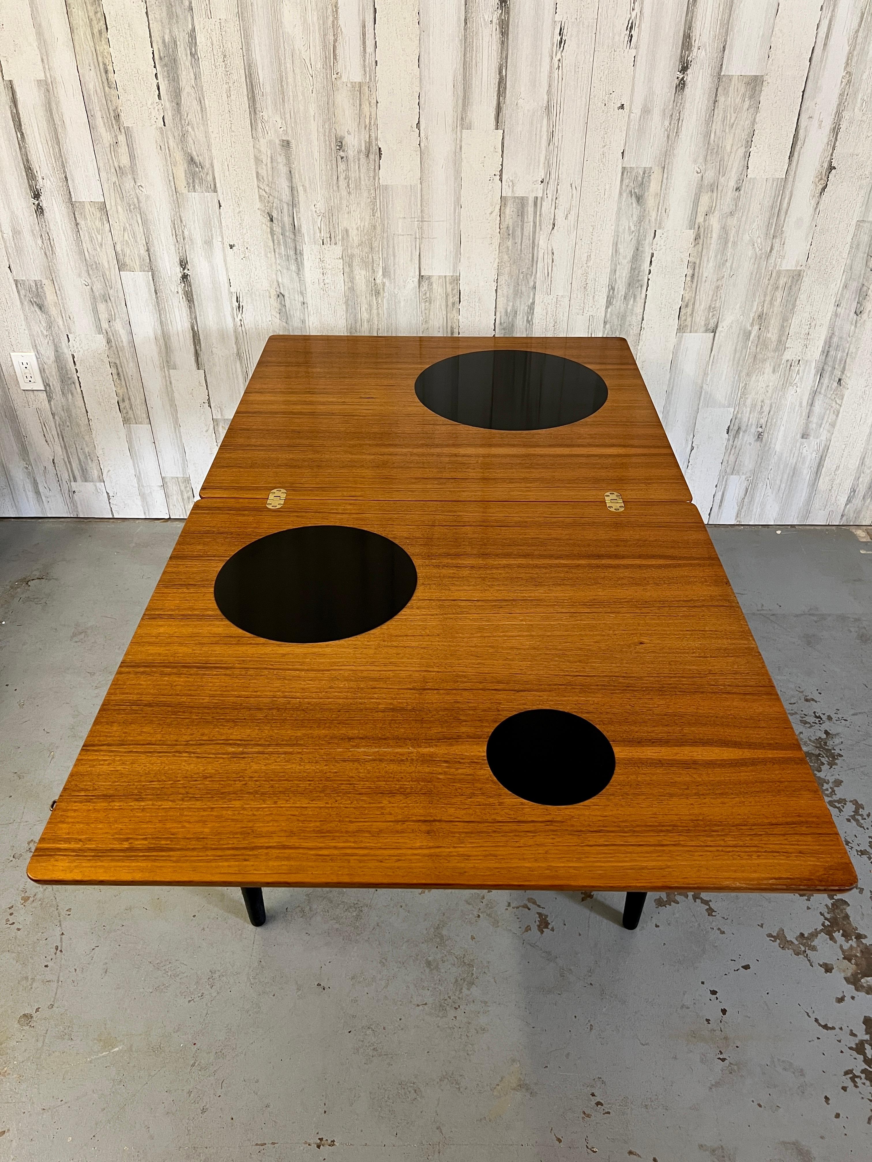 Teak flip top table with black laminate circular inlay, the legs are ebonized wood. The table measures 36