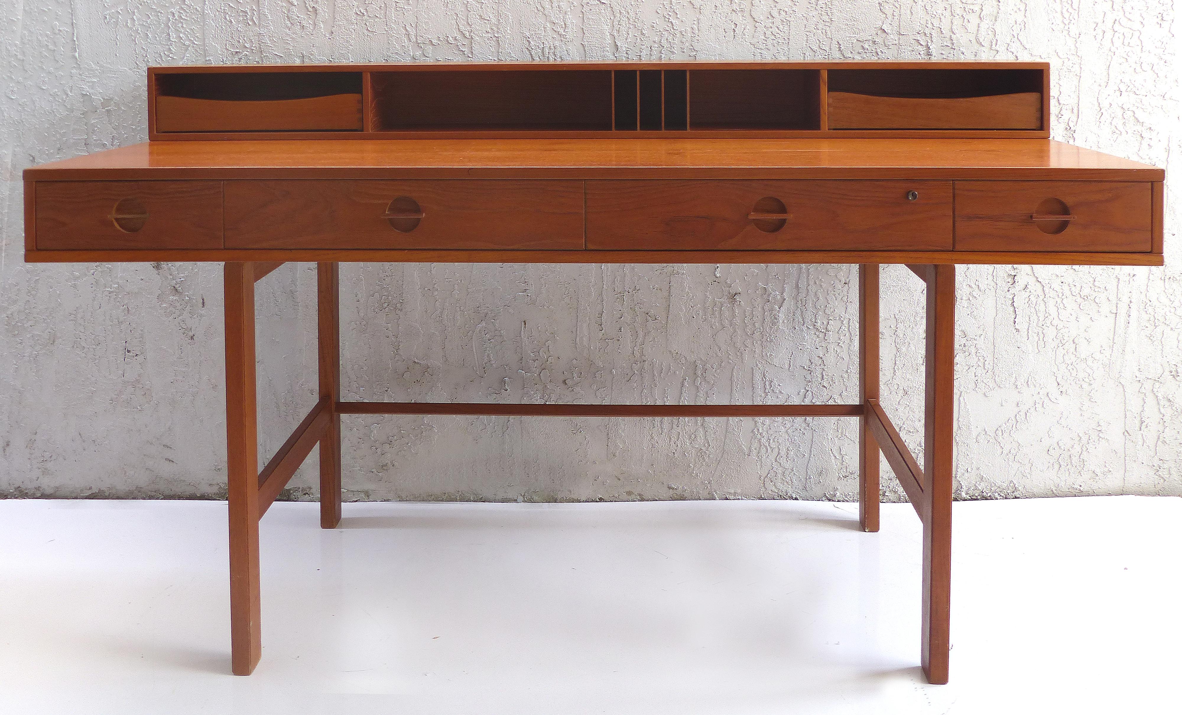 Offered for sale is an iconic Danish modern teak desk by Jens Quistgaard of Dansk for Peter Løvig Nielsen. The desk offers a very practical hinged gallery to top that flips down to expand into a partners desk or extended work surface. Measure: