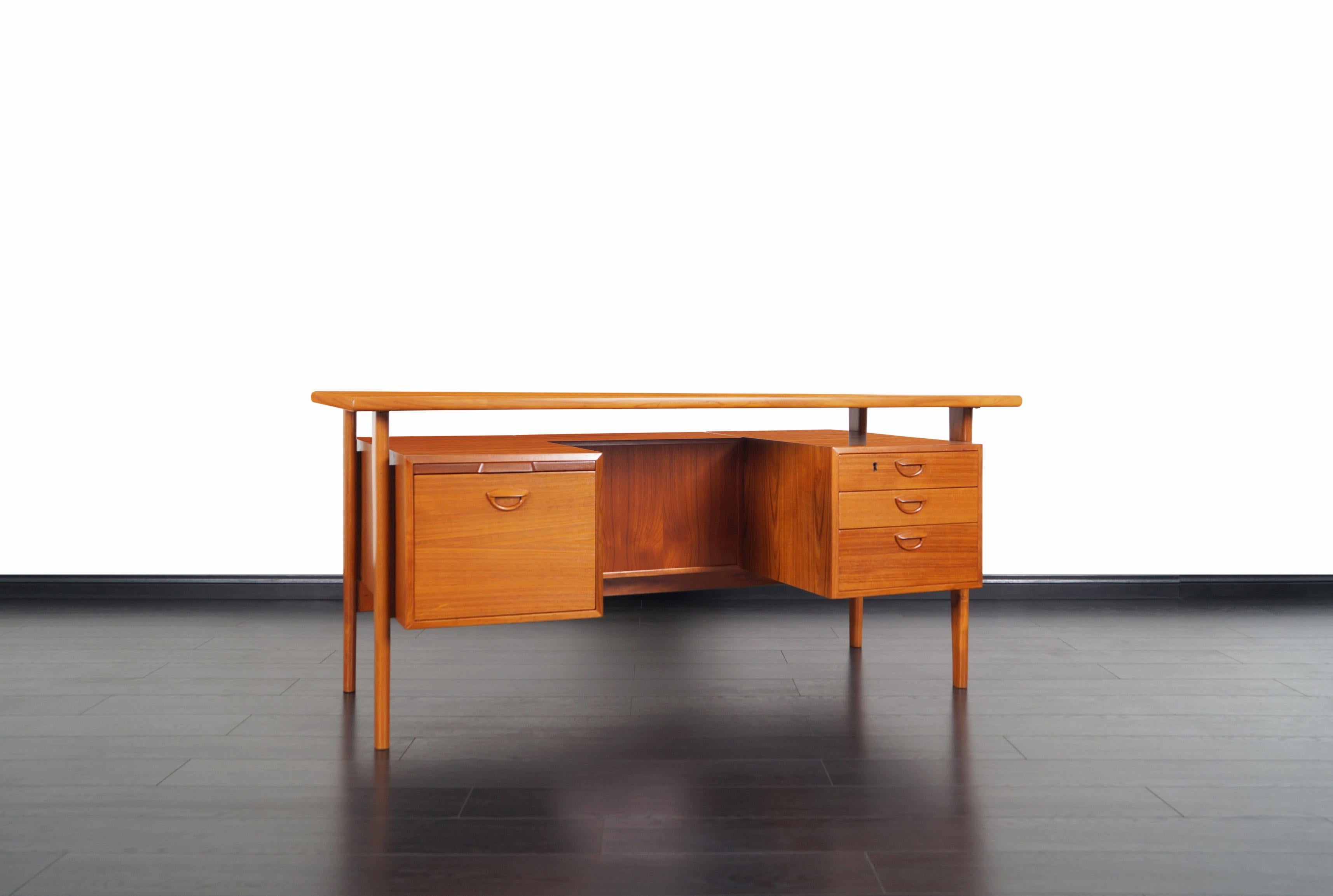 An amazing Danish executive teak desk designed by Kai Kristiansen for Feldballes Møbelfabrik, model FM60. This freestanding desk features three dovetailed drawers on the right and a file drawer with a pull-out writing surface on the left. On the