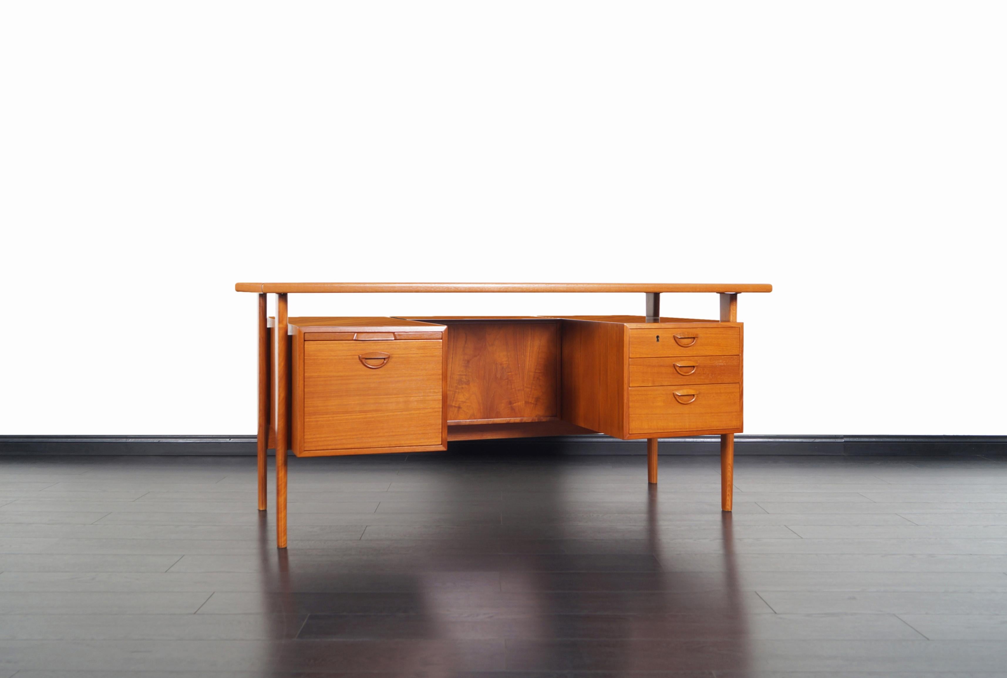 Amazing Danish teak executive desk designed by Kai Kristiansen for Feldballes Møbelfabrik, model FM60. This freestanding desk features three dovetailed drawers on the right and a file drawer with a pull-out writing surface on the left. On the