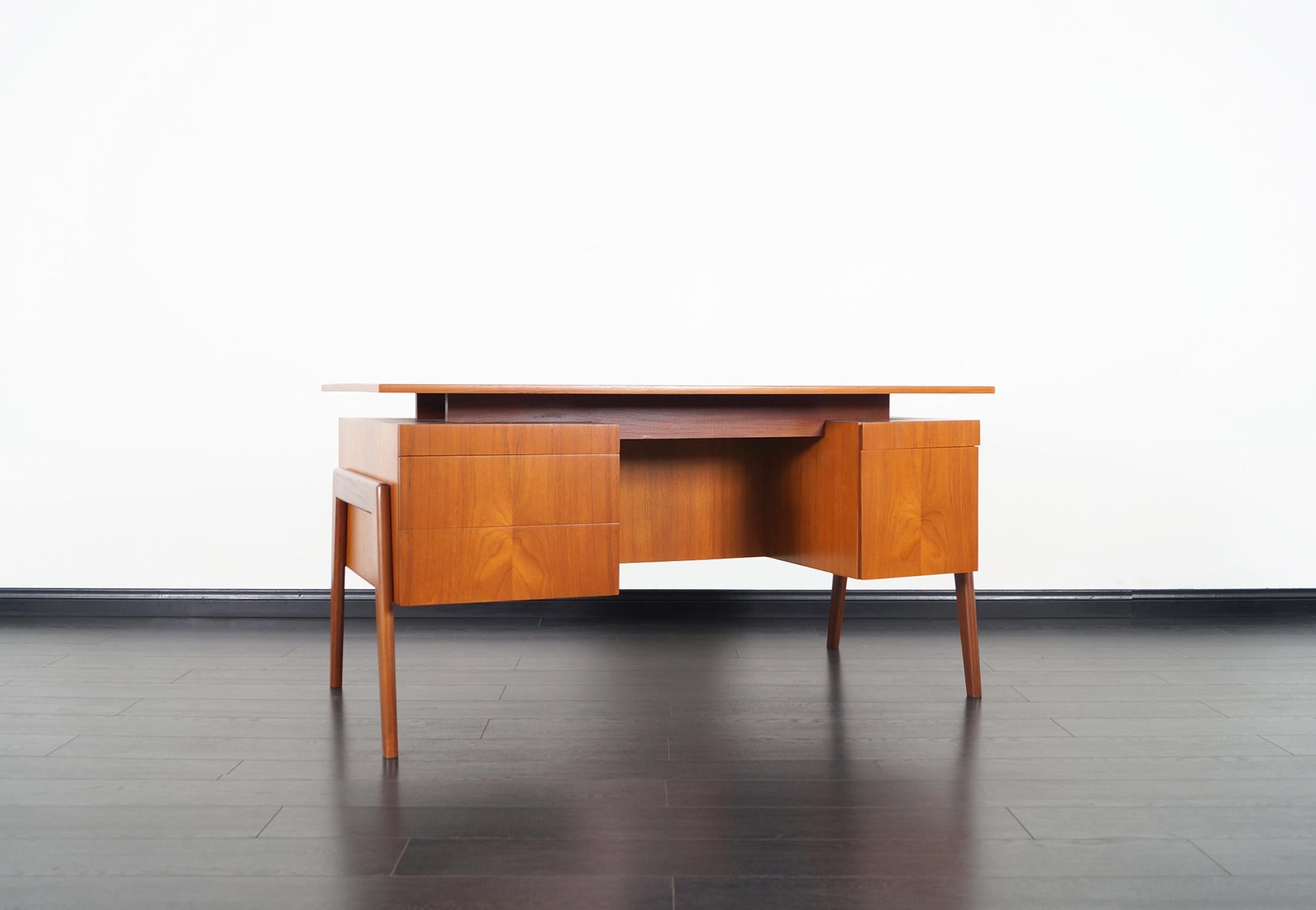 Stunning Danish modern teak desk designed and manufactured in Denmark, circa 1960s. The top has a floating top appearance. It features four dovetailed drawers and a file drawer. On the opposite side of the desk there's an extra storage unit,