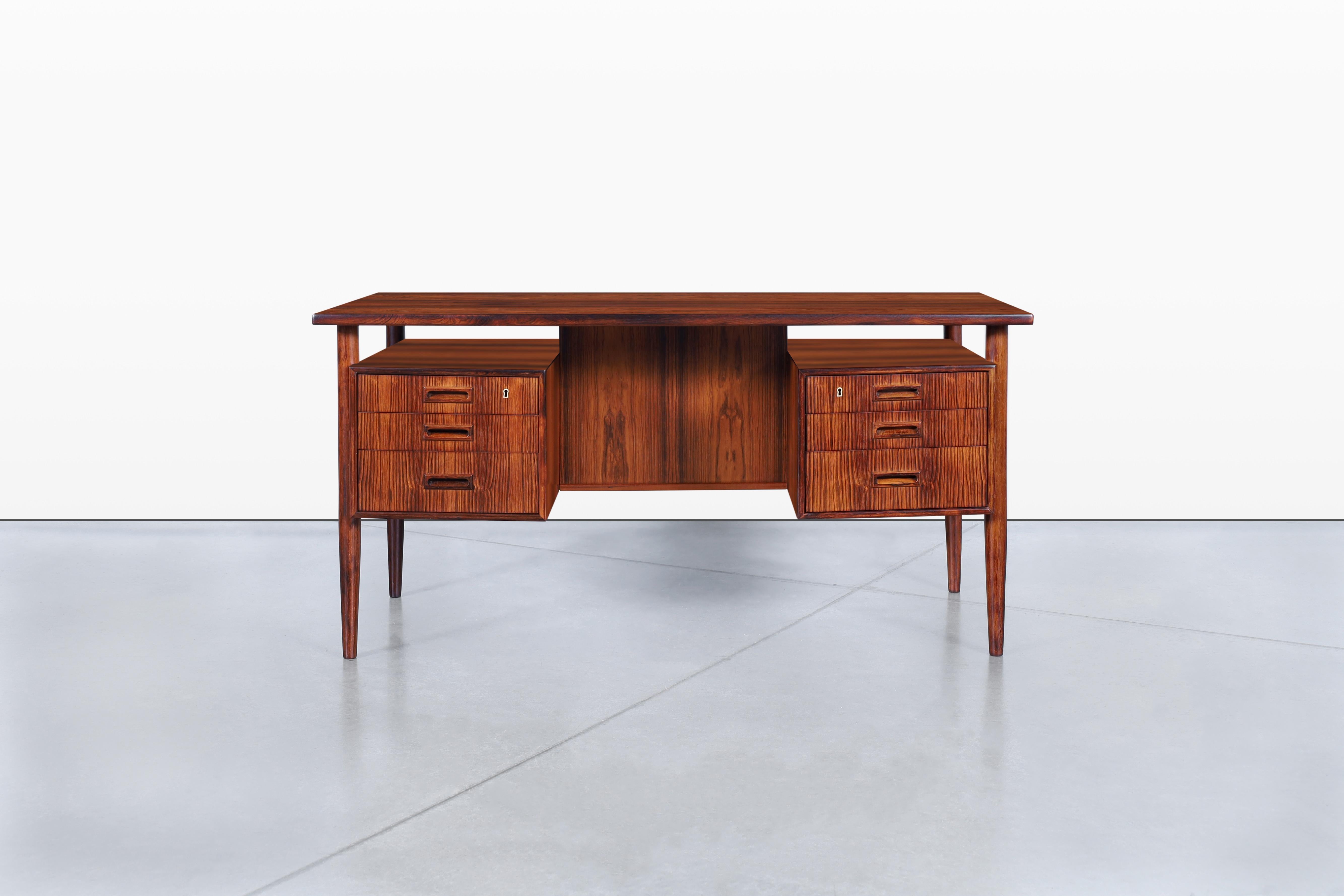 Introducing a stunning Danish modern floating top rosewood desk, expertly designed by Johannes Sorth for Bornholm Møbelfabrik in the 1960s. This exquisite piece showcases six dovetail drawers, with the top drawers featuring locks for securely